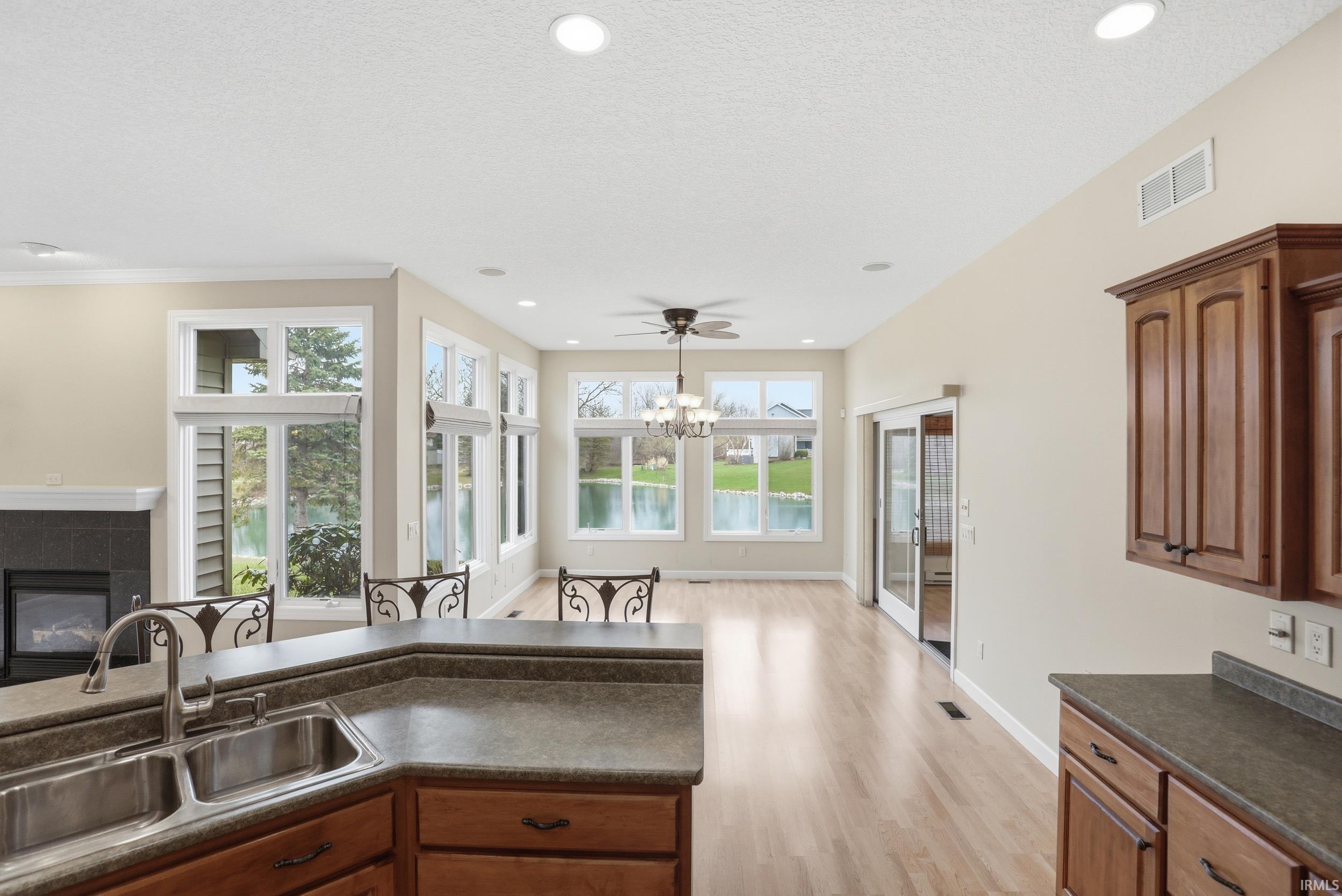Kitchen with dark countertops, wood finish cabinetry, a fireplace, light wood finished floors, and a textured ceiling