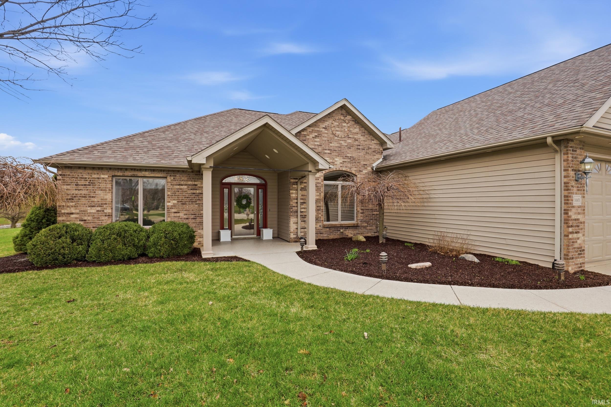 View of front facade with roof with shingles, brick siding, an attached garage, and a front yard