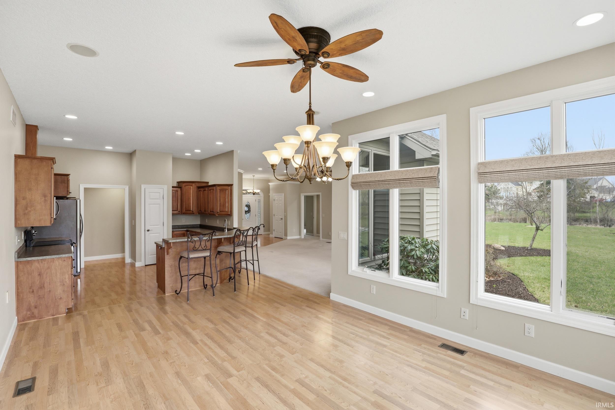 Kitchen featuring a kitchen bar, wood finish cabinetry, a center island, suspended lighting, and light wood-style flooring