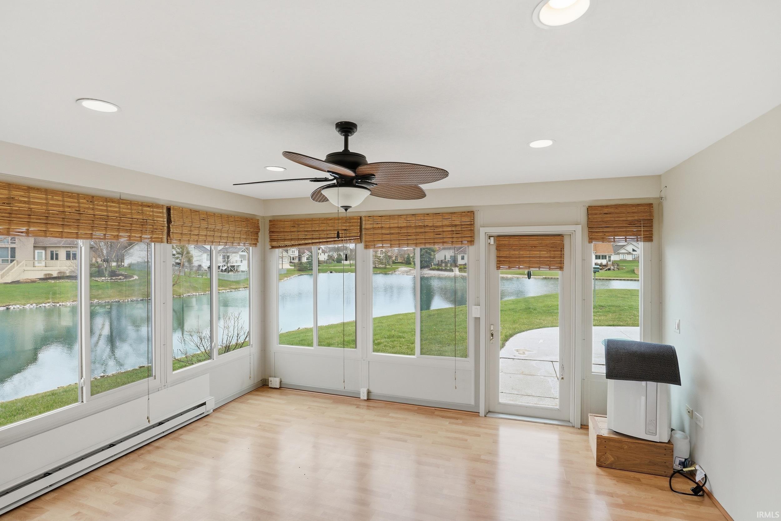 Unfurnished sunroom featuring ceiling fan, a baseboard heating unit, wood finished floors, healthy amount of natural light, and recessed lighting