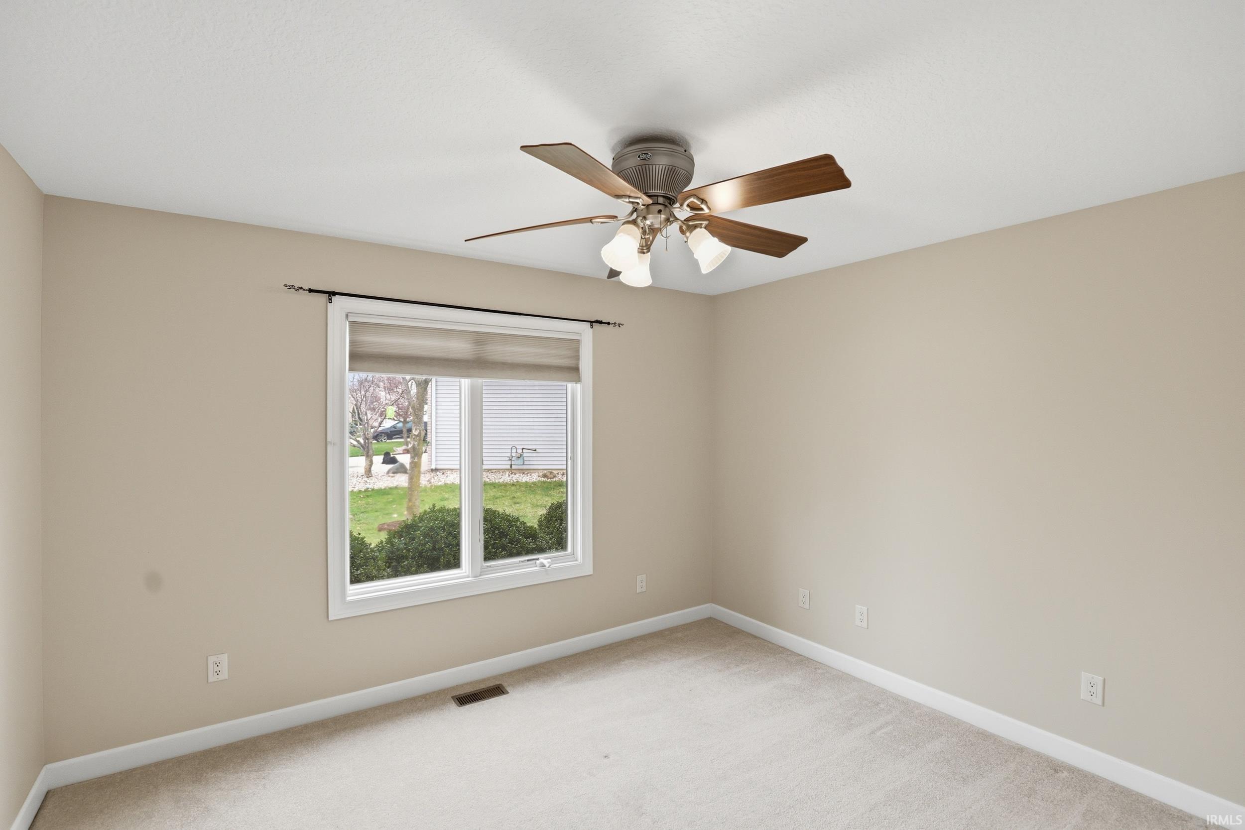 Empty room featuring a ceiling fan and light carpet