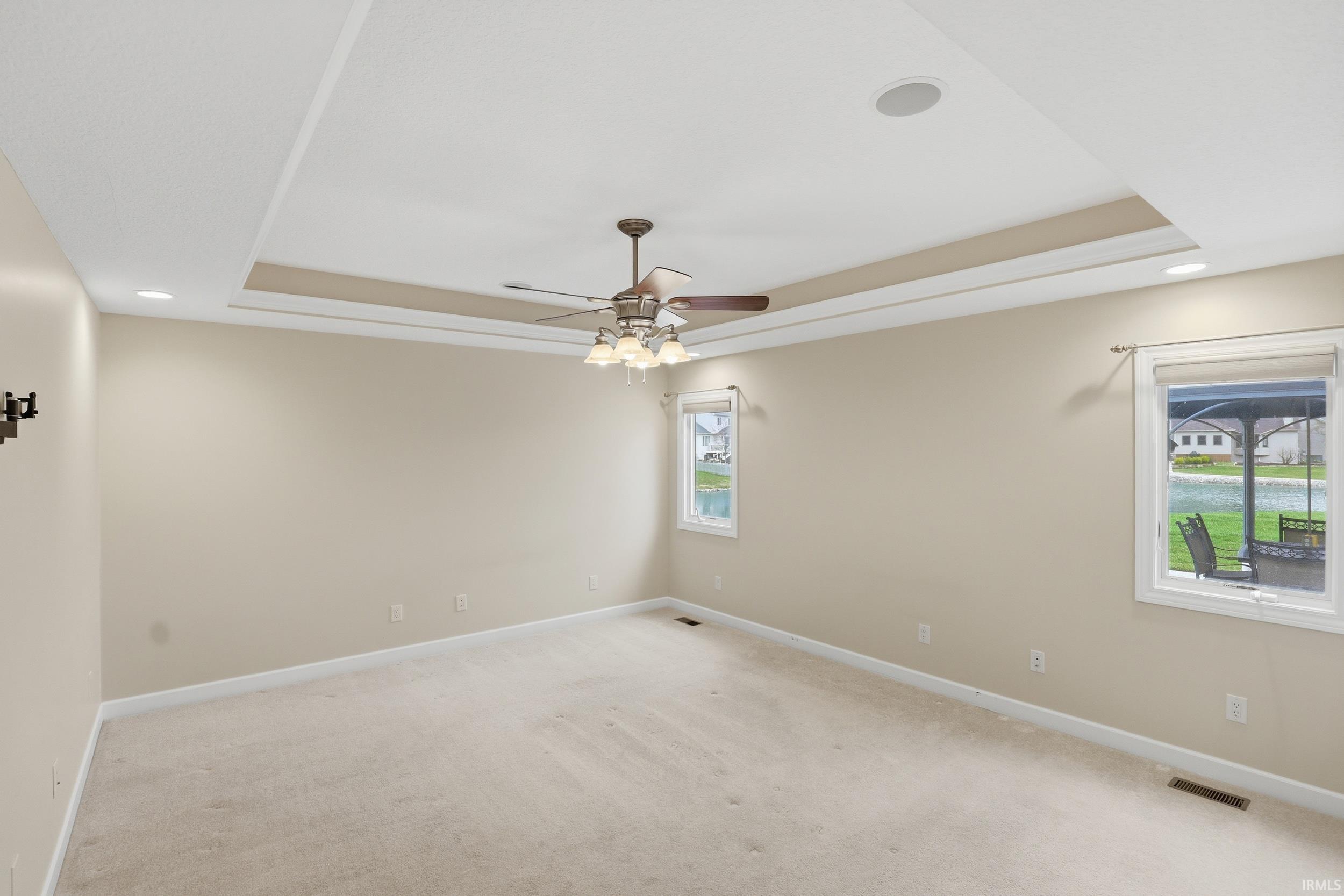 Spare room with recessed lighting, light carpet, a tray ceiling, and ceiling fan