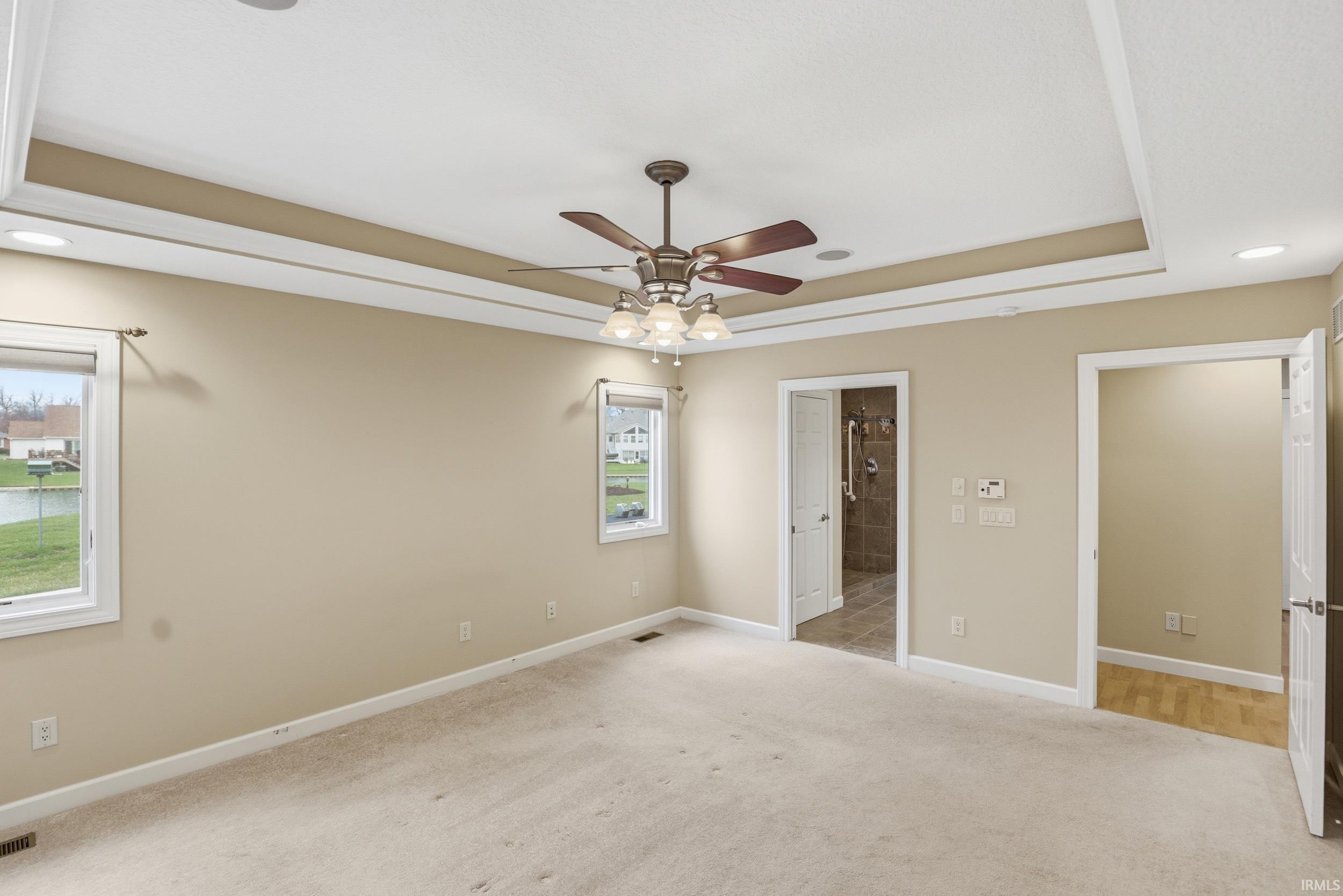 Unfurnished bedroom featuring a tray ceiling, light colored carpet, a ceiling fan, and recessed lighting