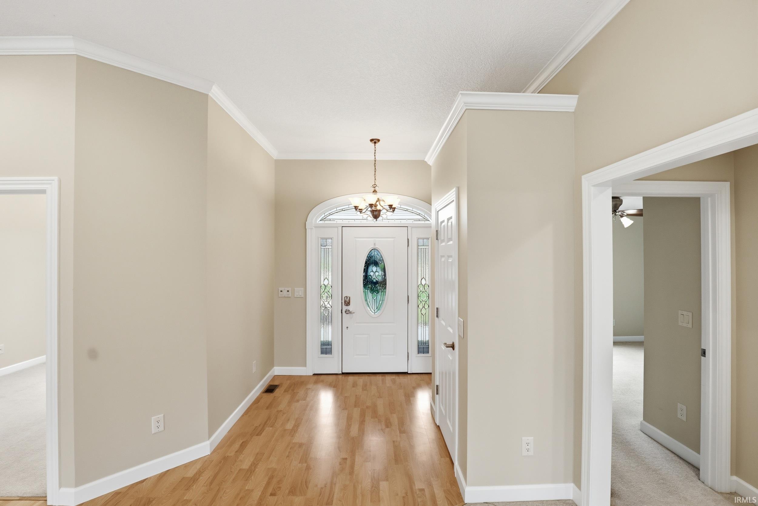 Foyer featuring hanging lights, crown molding, ceiling fan, and light wood-style flooring
