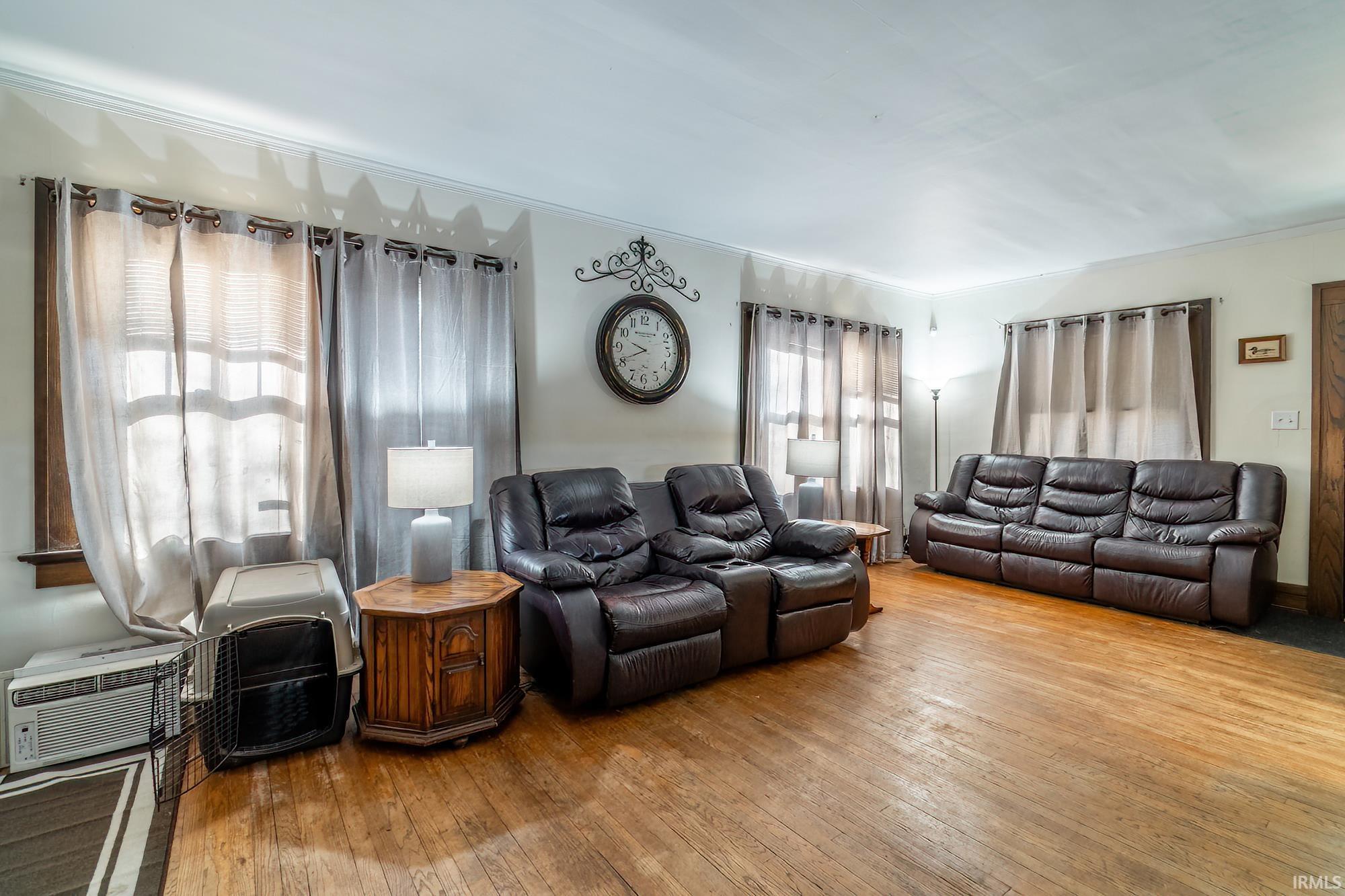 Living area with wood-type flooring and ornamental molding