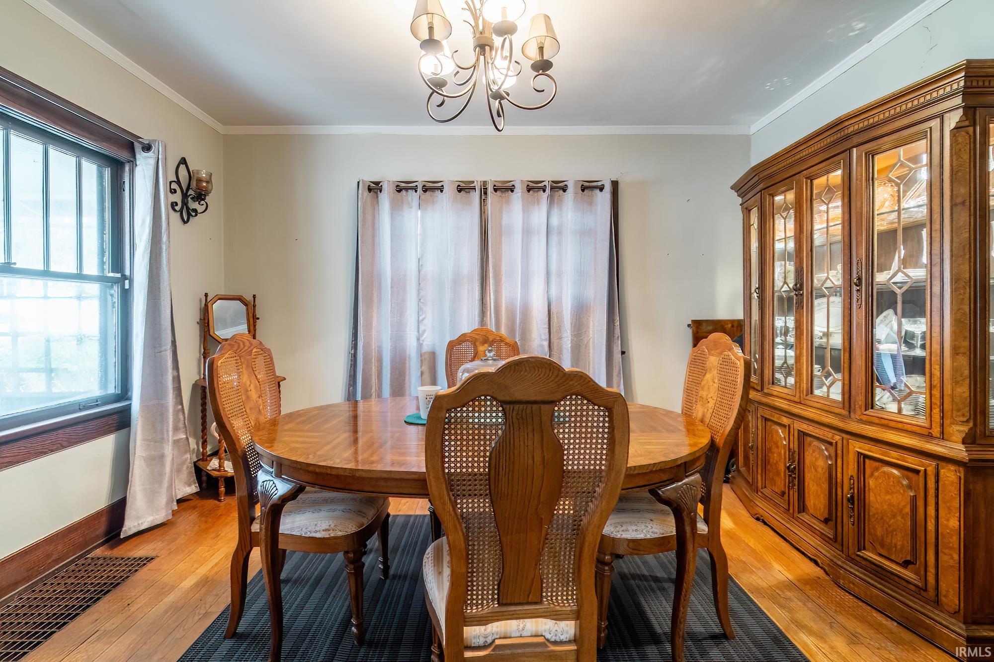 Dining area featuring hanging lights, light wood-style flooring, and crown molding