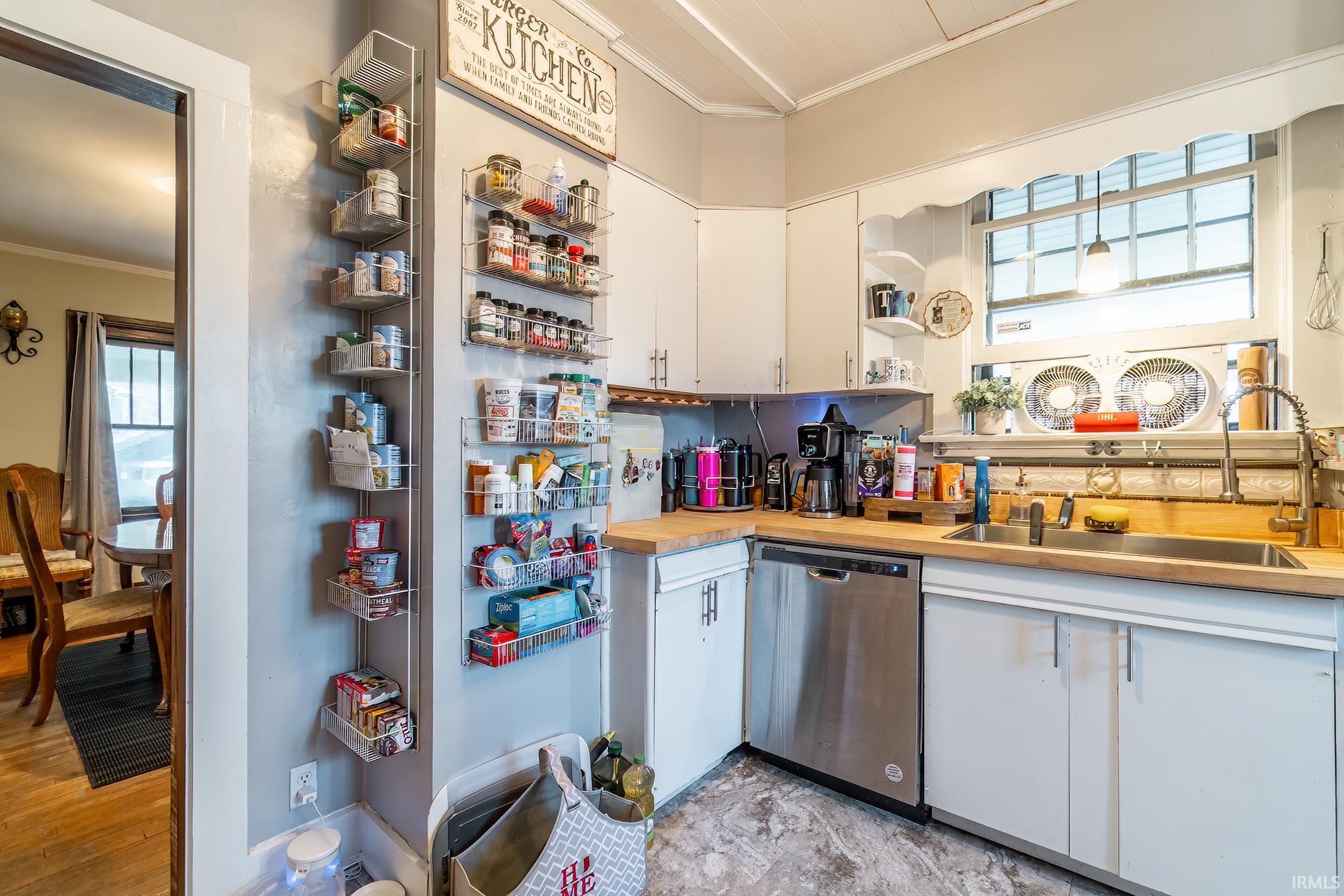 Kitchen with ornamental molding, dishwasher, white cabinetry, and open shelves