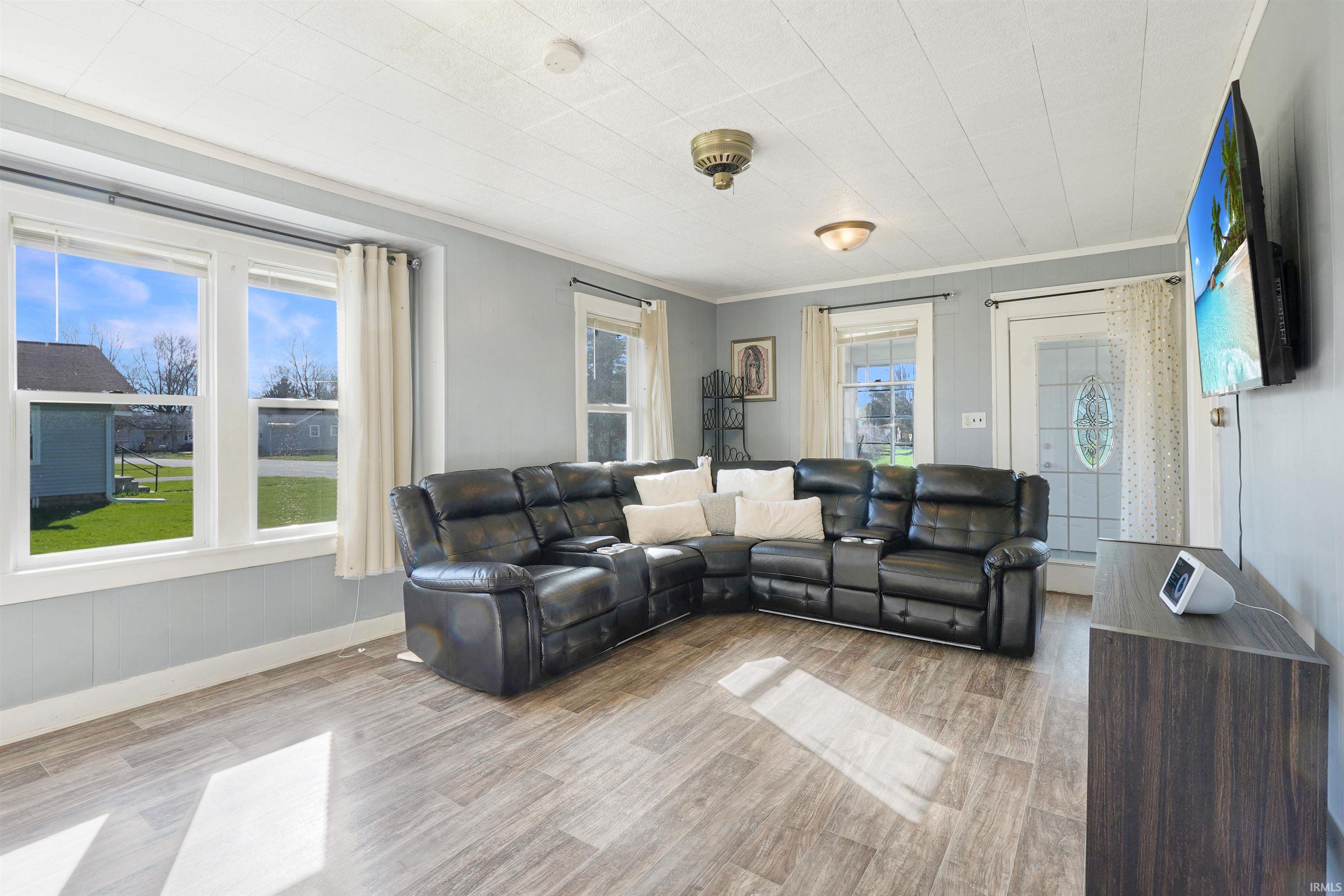 Living room with light wood-type flooring, healthy amount of natural light, and crown molding