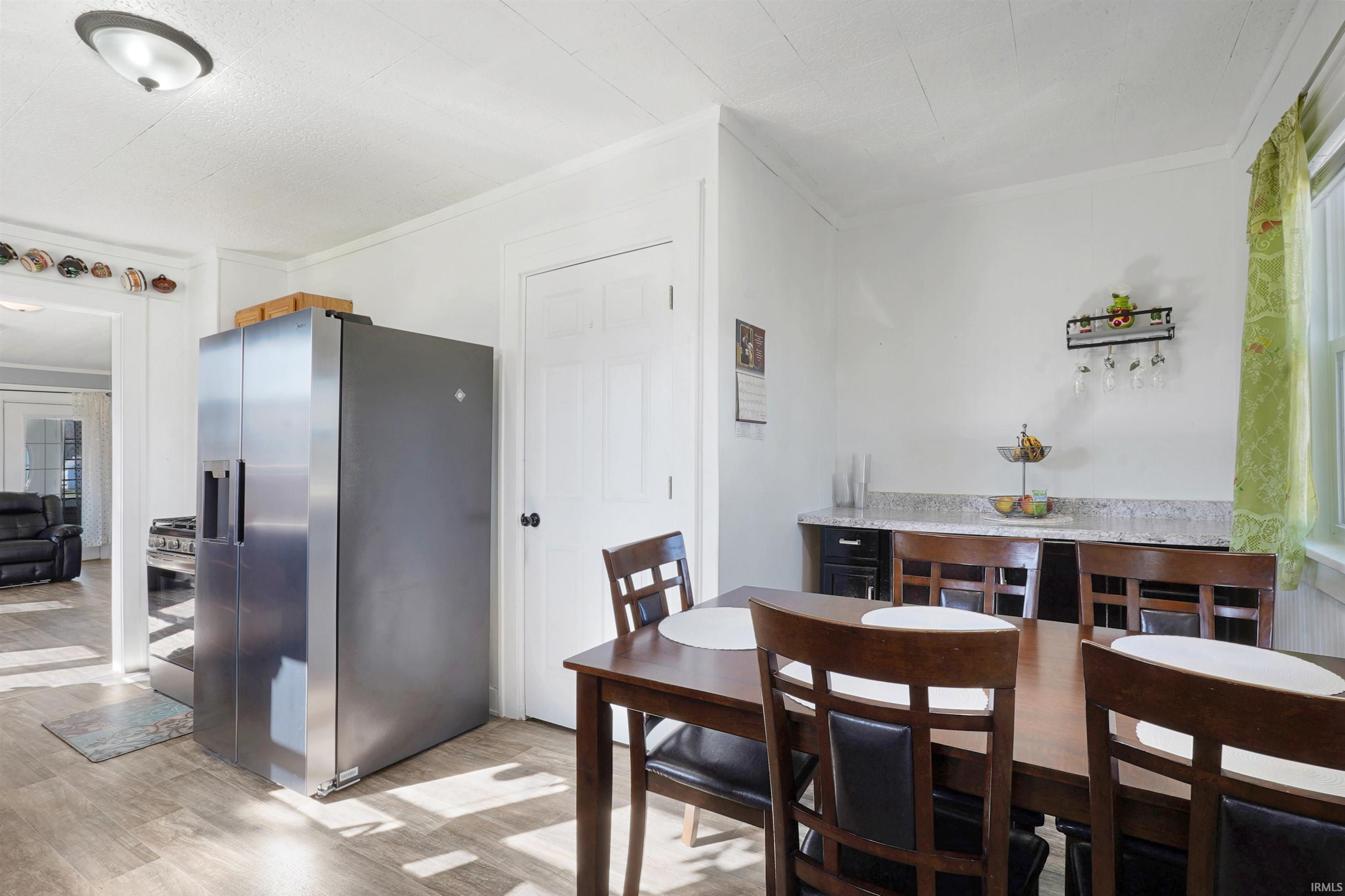 Dining area with light wood-style flooring and crown molding