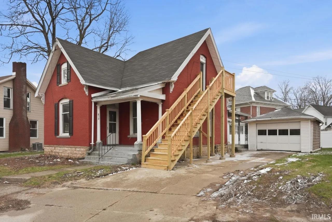 View of front of house with a shingled roof, a garage, brick siding, concrete driveway, and an outdoor structure