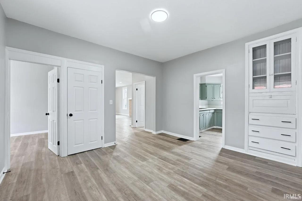 Unfurnished living room featuring light wood finished floors and baseboards