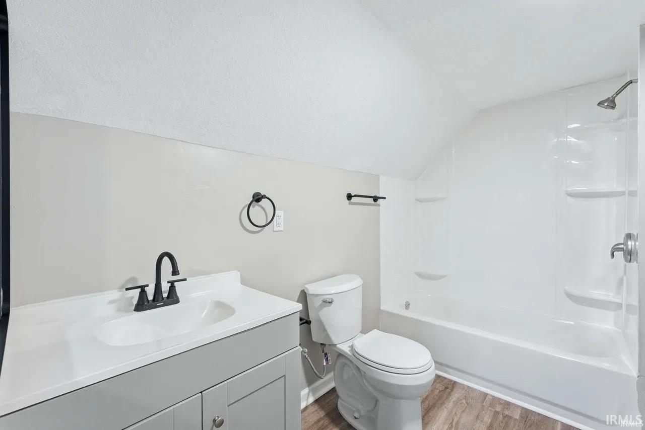 Full bathroom featuring lofted ceiling, vanity, light wood-type flooring, and shower / tub combination