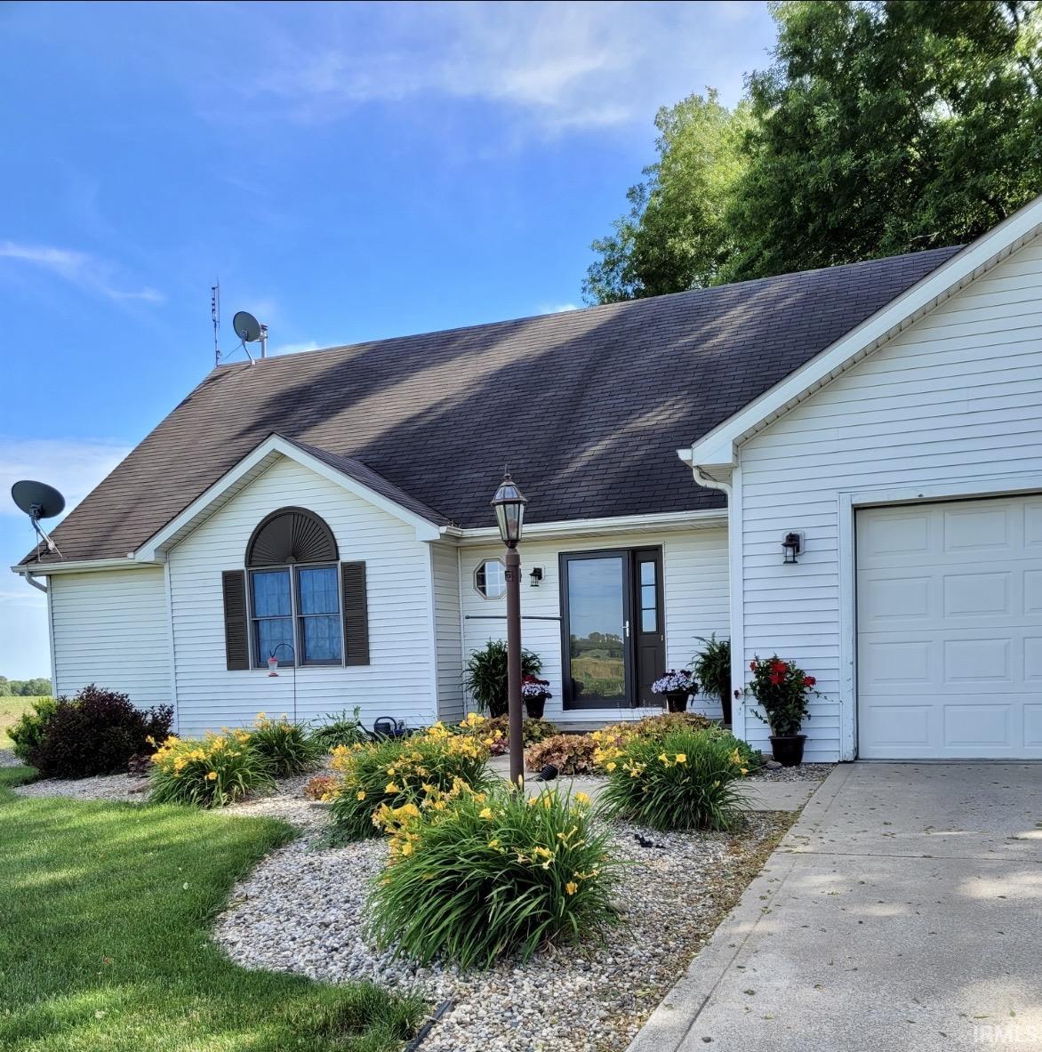 Ranch-style home featuring a shingled roof and a garage