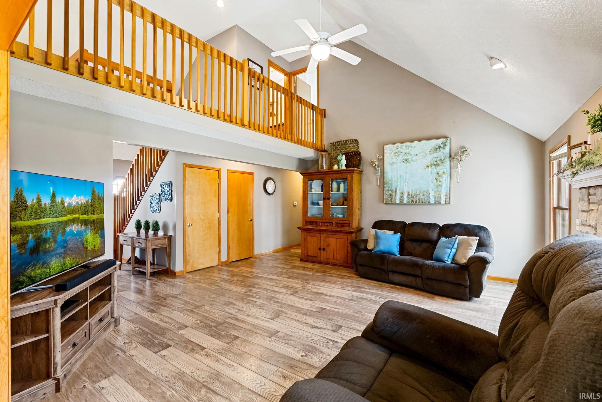 Living area with ceiling fan, light wood-type flooring, and lofted ceiling