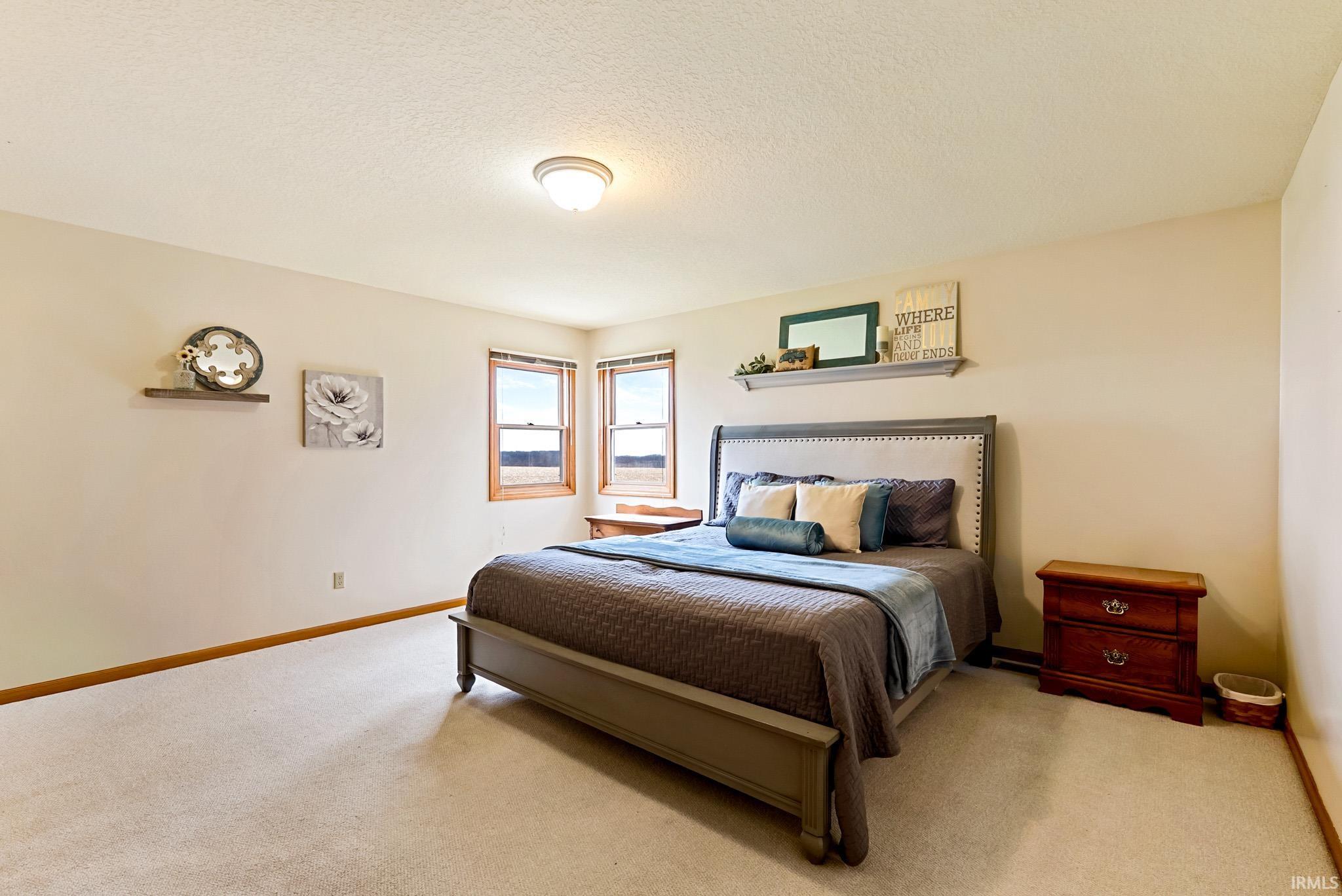 Carpeted bedroom featuring baseboards and a textured ceiling