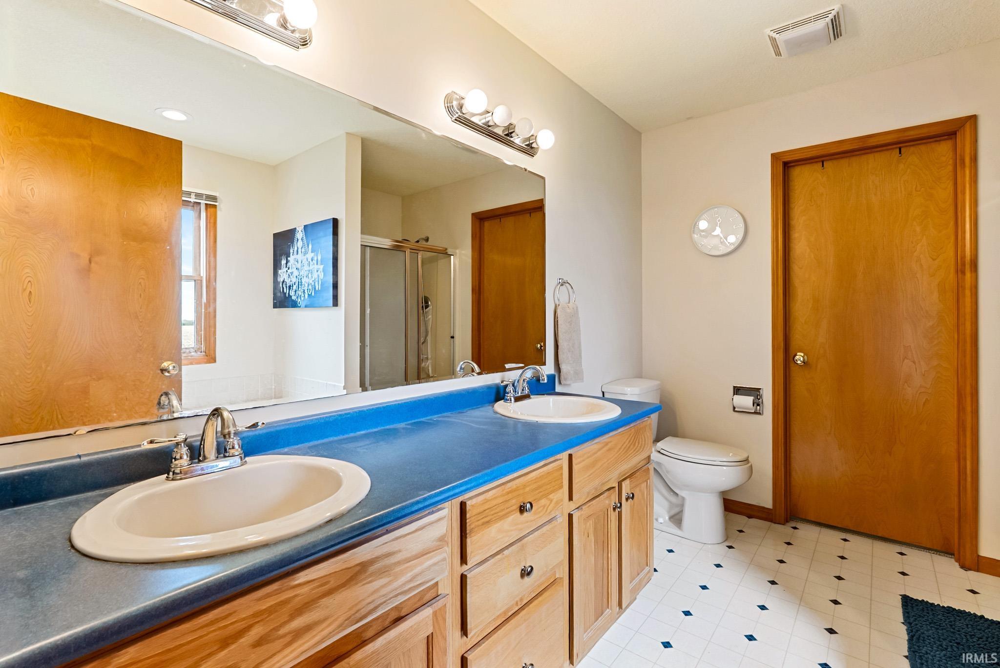 Bathroom featuring double vanity, a shower stall, and light flooring