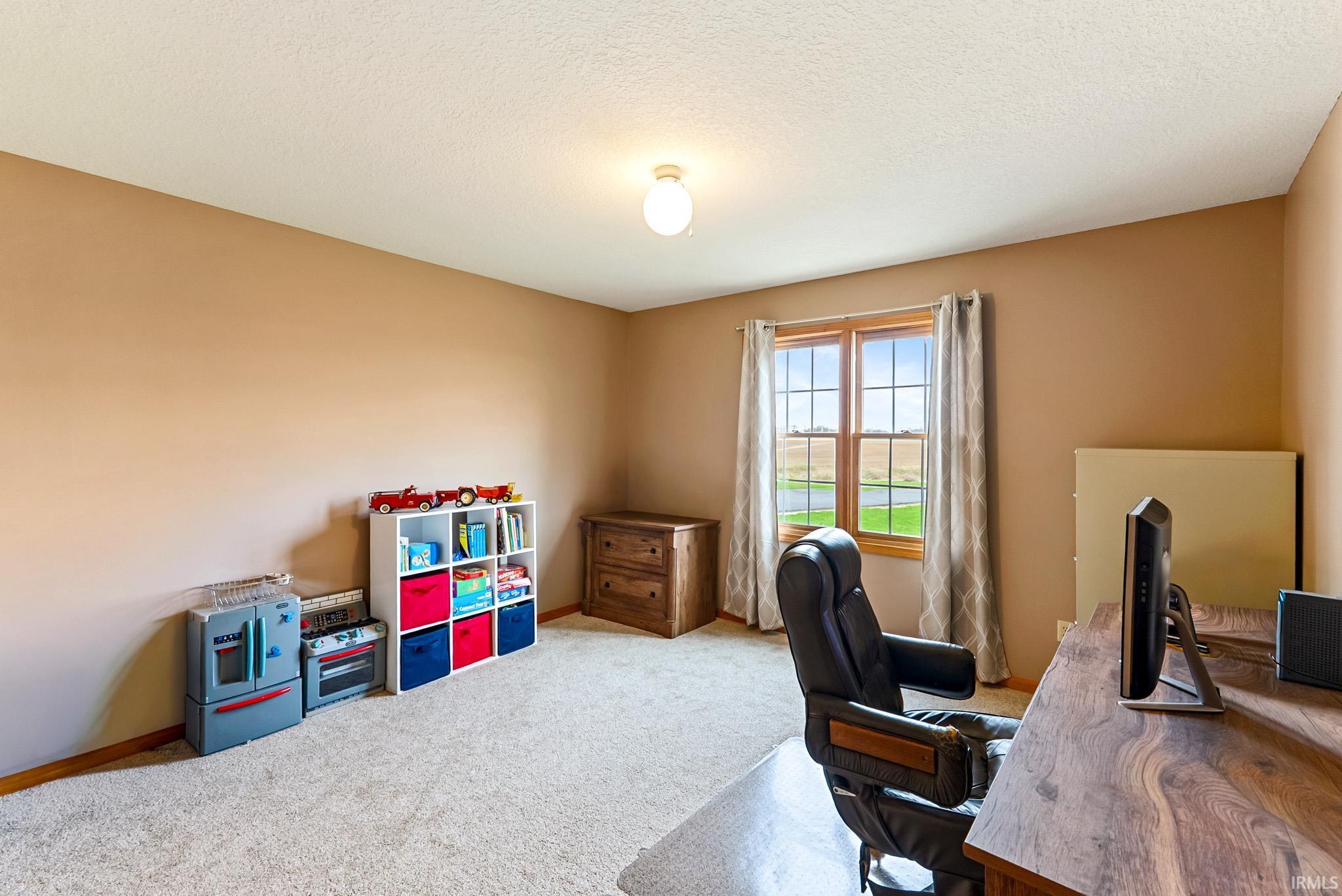 Carpeted office with baseboards and a textured ceiling