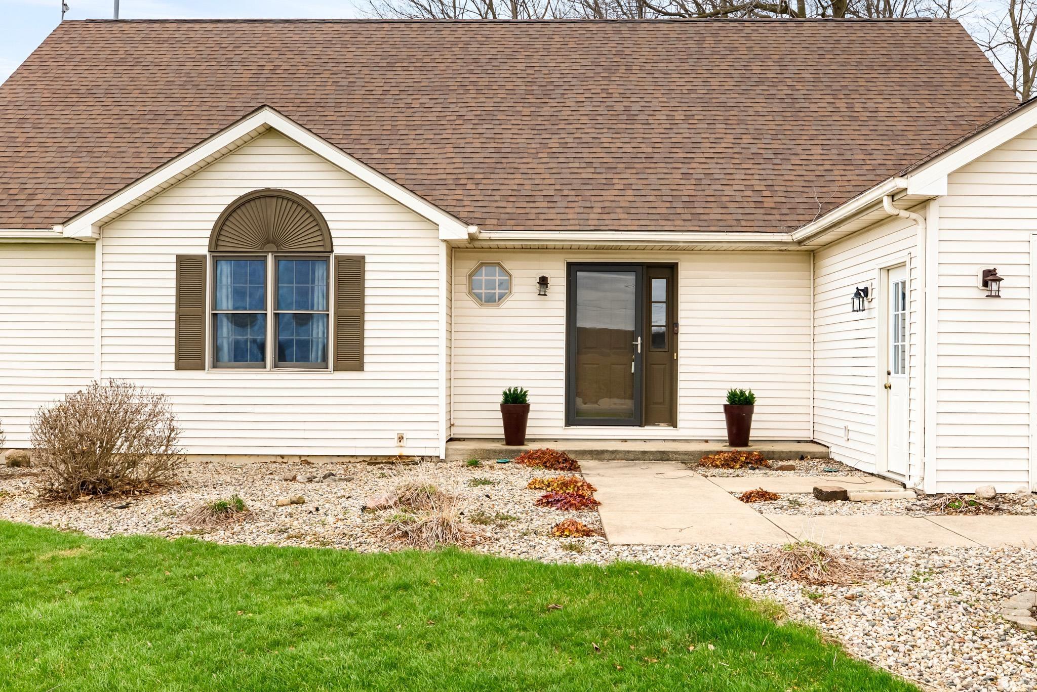 View of front facade with roof with shingles and a front lawn