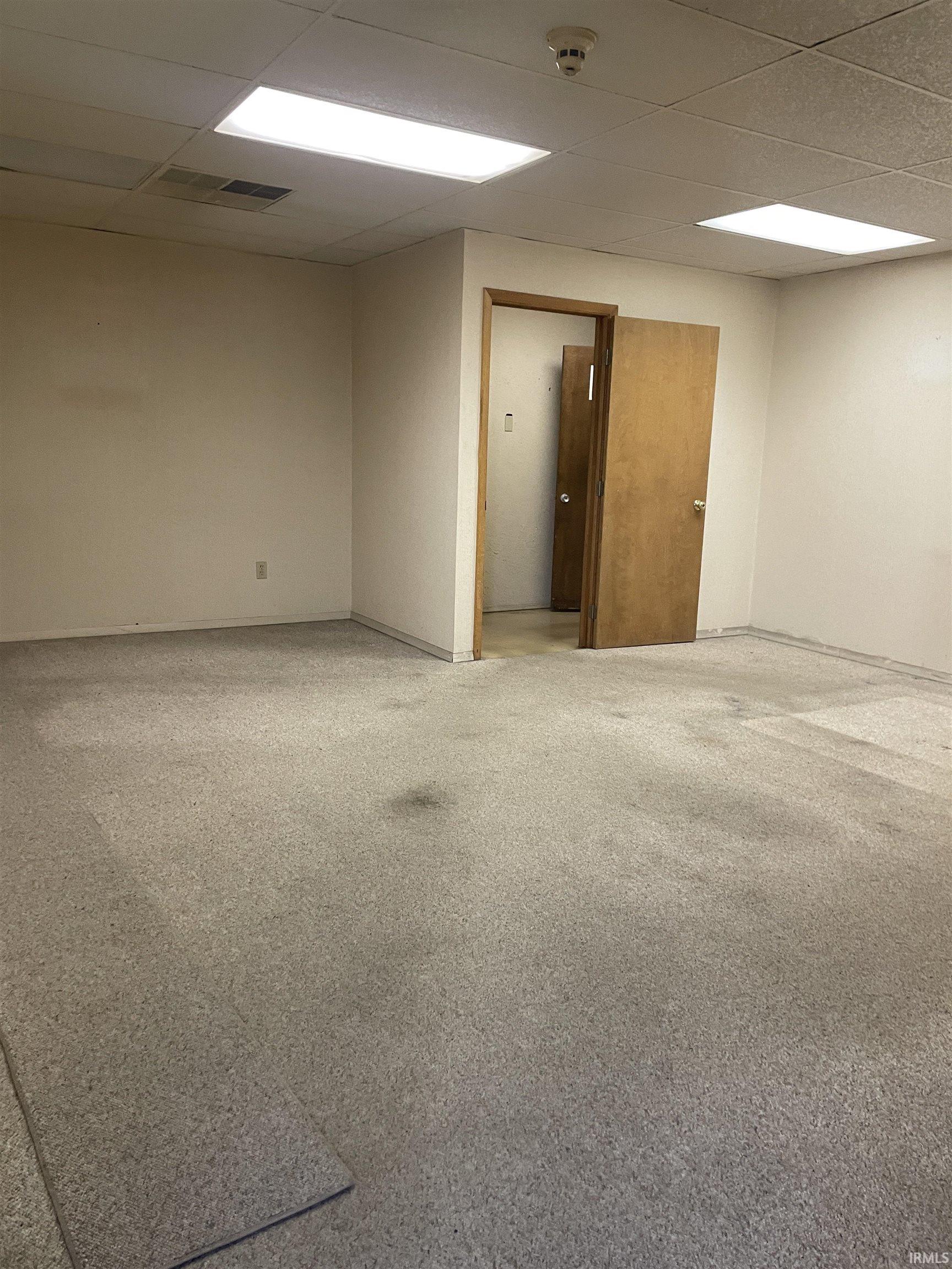 Empty room featuring a paneled ceiling and light carpet