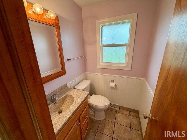 Bathroom with vanity, wainscoting, and light tile patterned floors