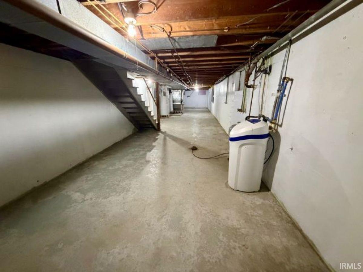 Unfinished basement with a water softener system, heating unit, and water heater