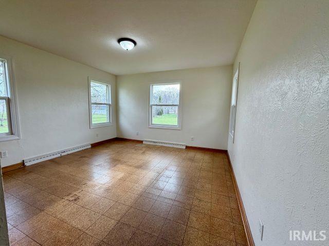 Unfurnished room with baseboard heating, tile patterned floors, and a textured wall