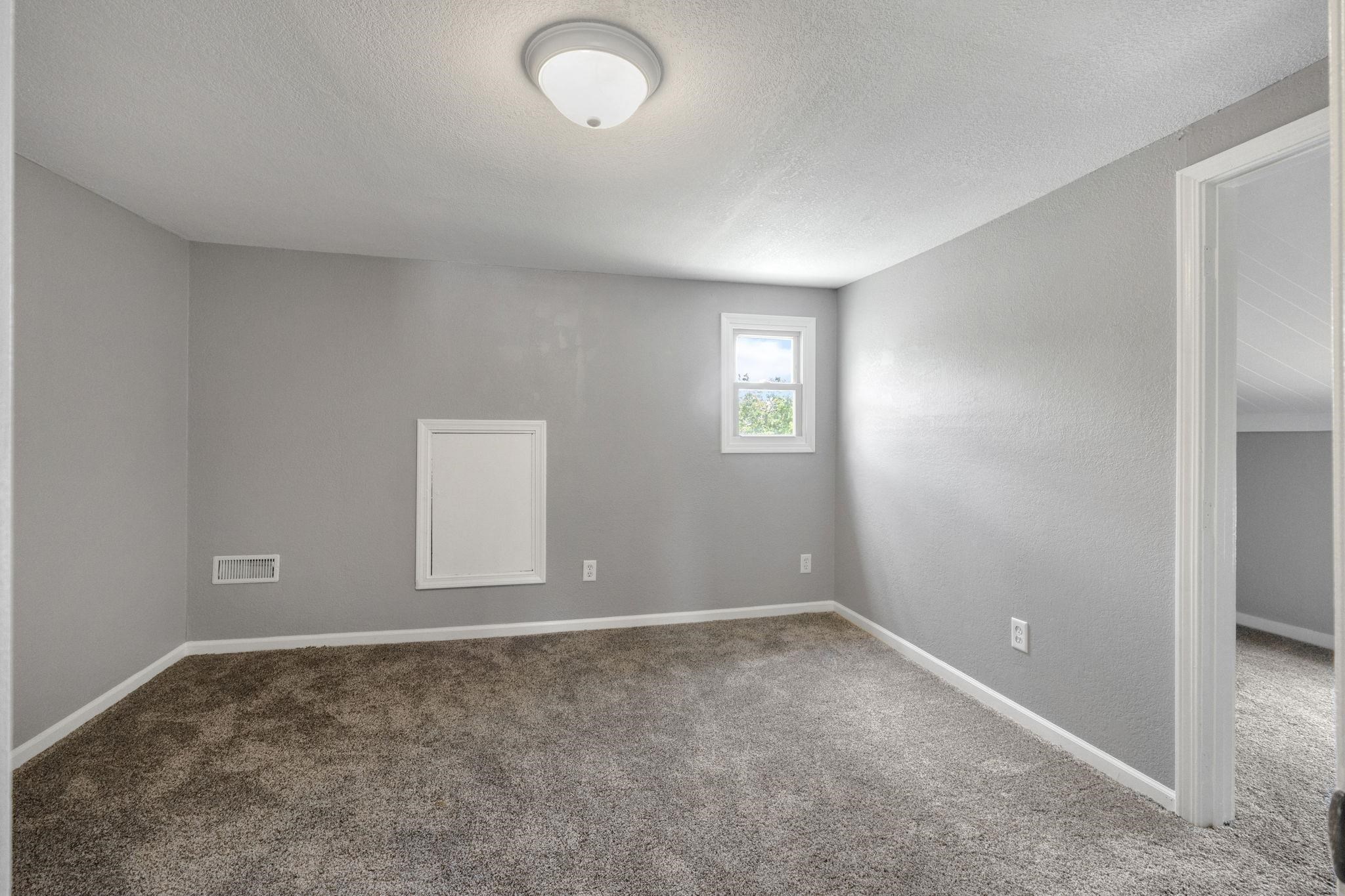 Carpeted spare room featuring a textured ceiling and a textured wall
