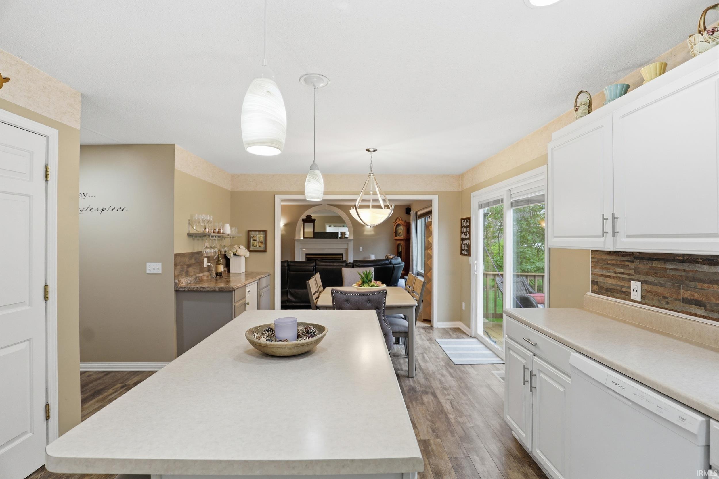 Kitchen with light countertops, dishwasher, light wood-type flooring, and decorative light fixtures