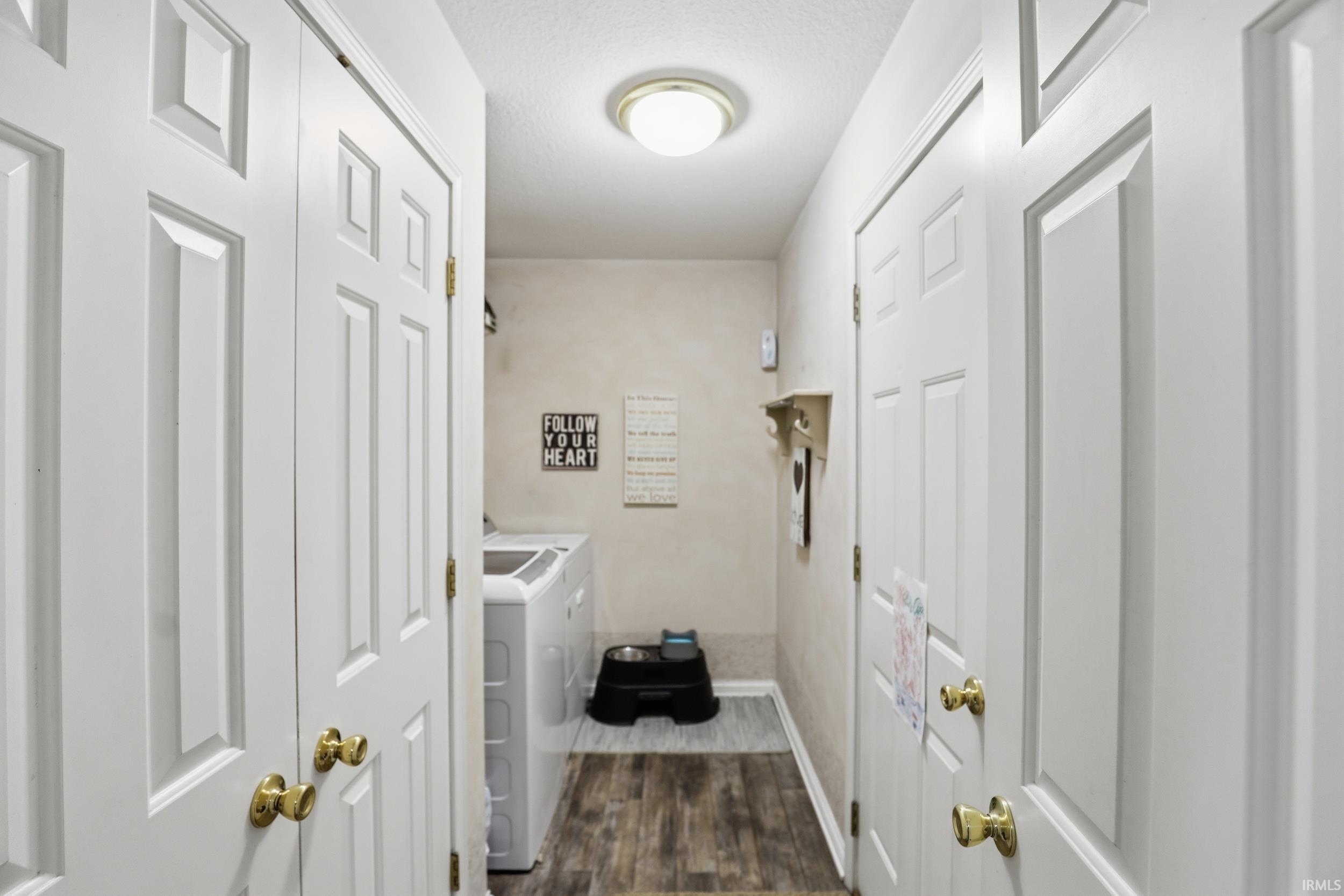 Laundry area with dark wood-type flooring, separate washer and dryer, and a textured ceiling