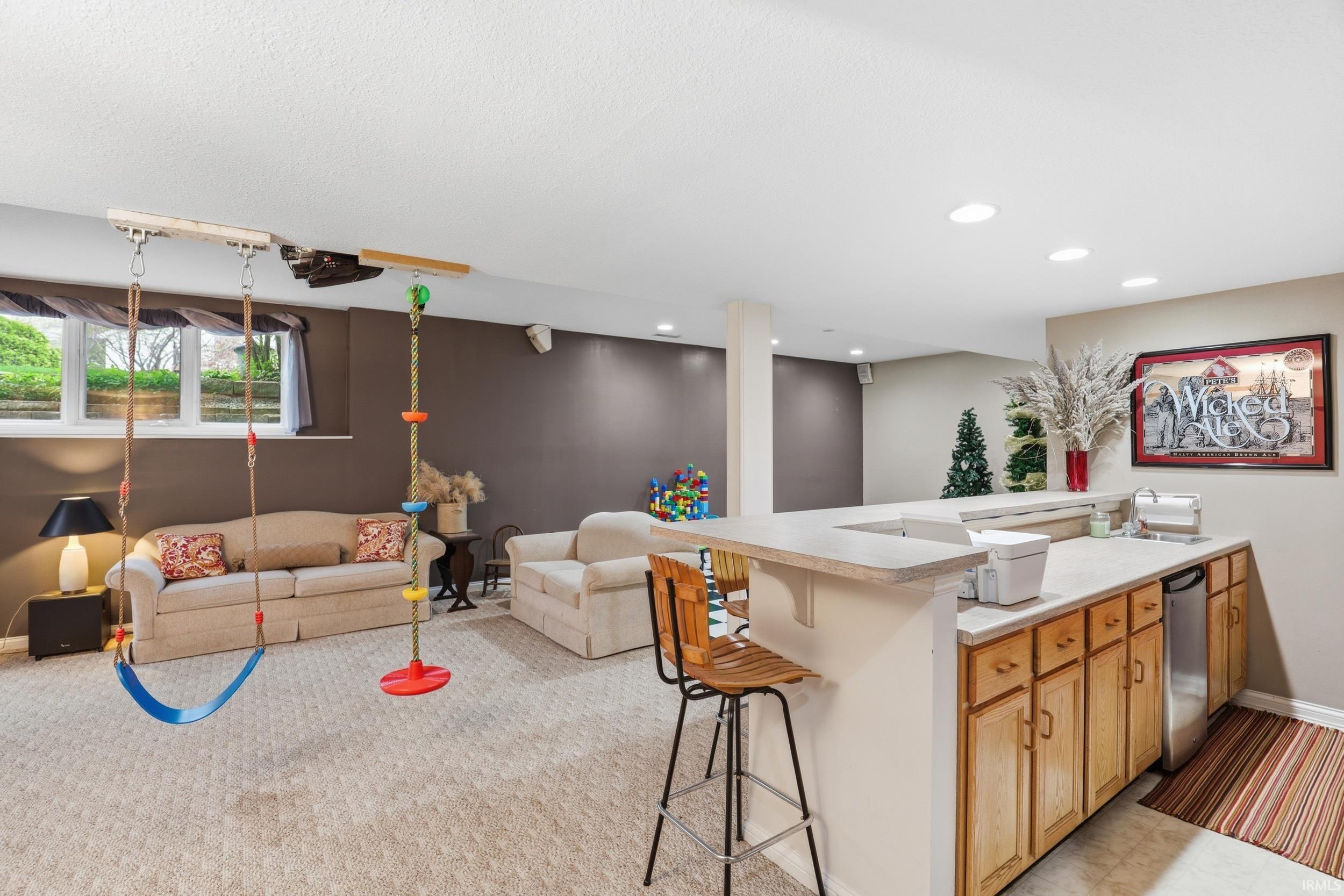 Kitchen with light countertops, a kitchen breakfast bar, open floor plan, dishwasher, and light carpet