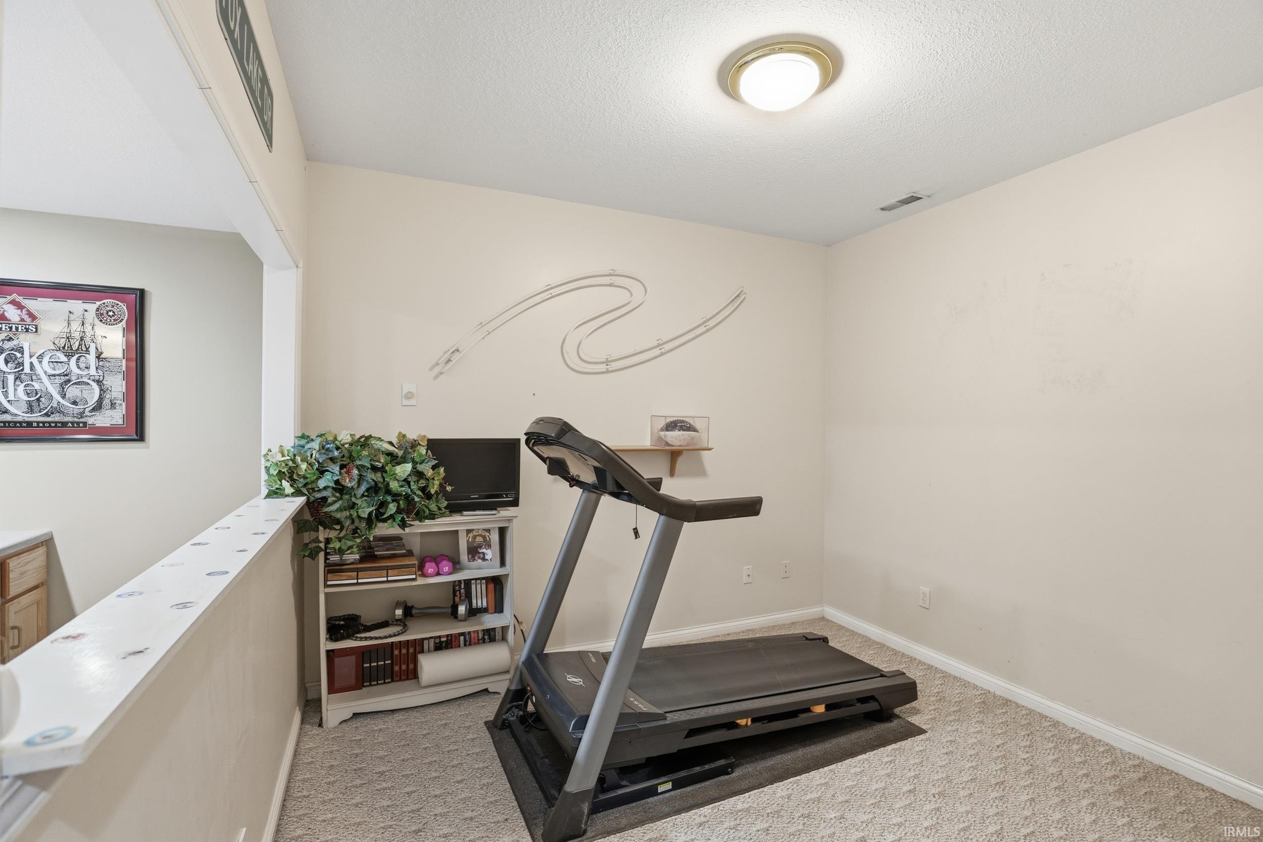 Exercise room with light carpet and a textured ceiling