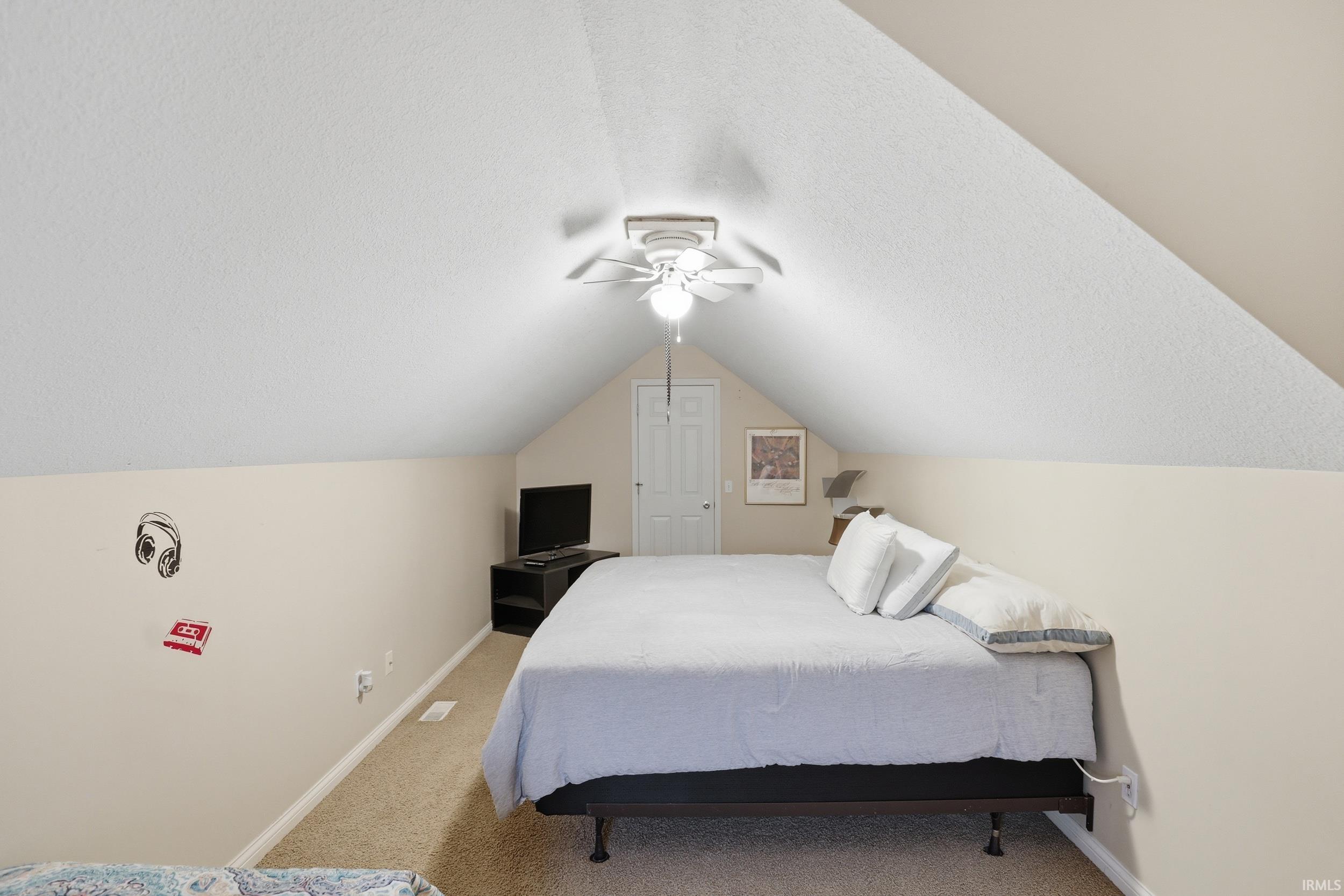 Bedroom with a textured ceiling, light carpet, and ceiling fan