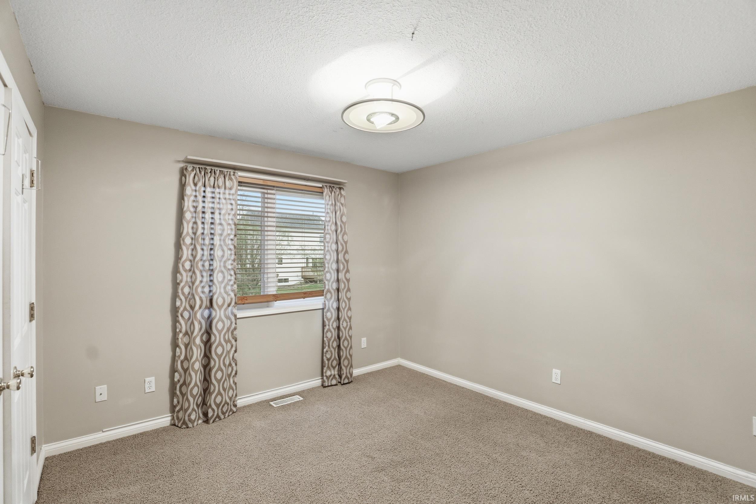 Spare room with light colored carpet and a textured ceiling