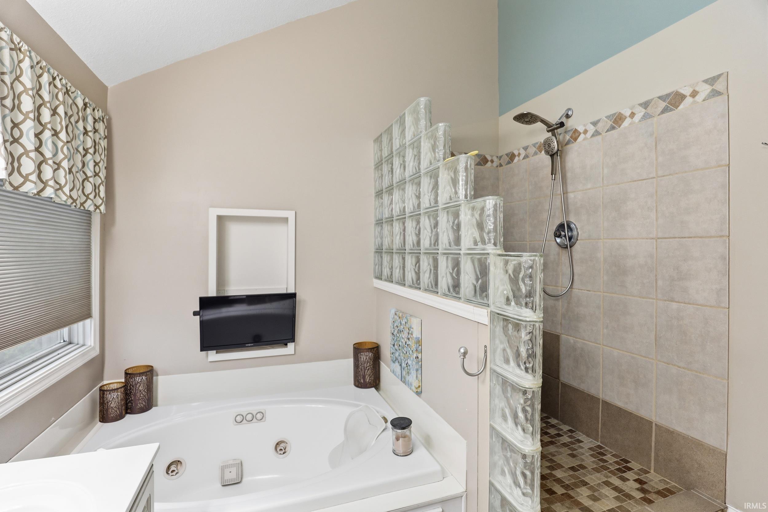 Bathroom with a walk in shower, vanity, and a whirlpool tub