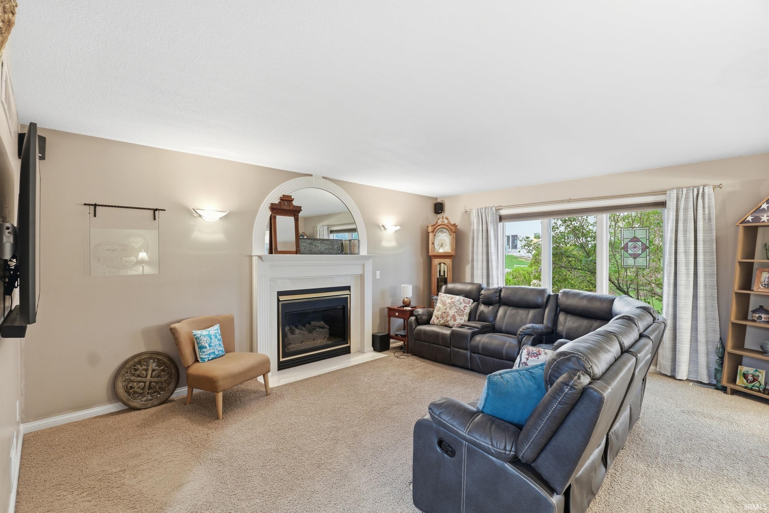 Living area with a glass covered fireplace and light carpet