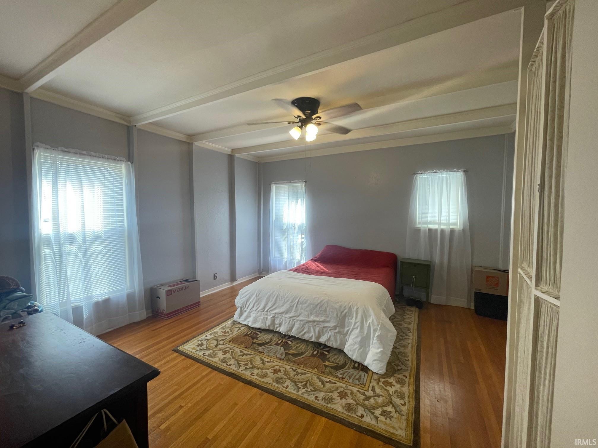 Bedroom featuring light hardwood floors, a ceiling fan, and beamed ceiling