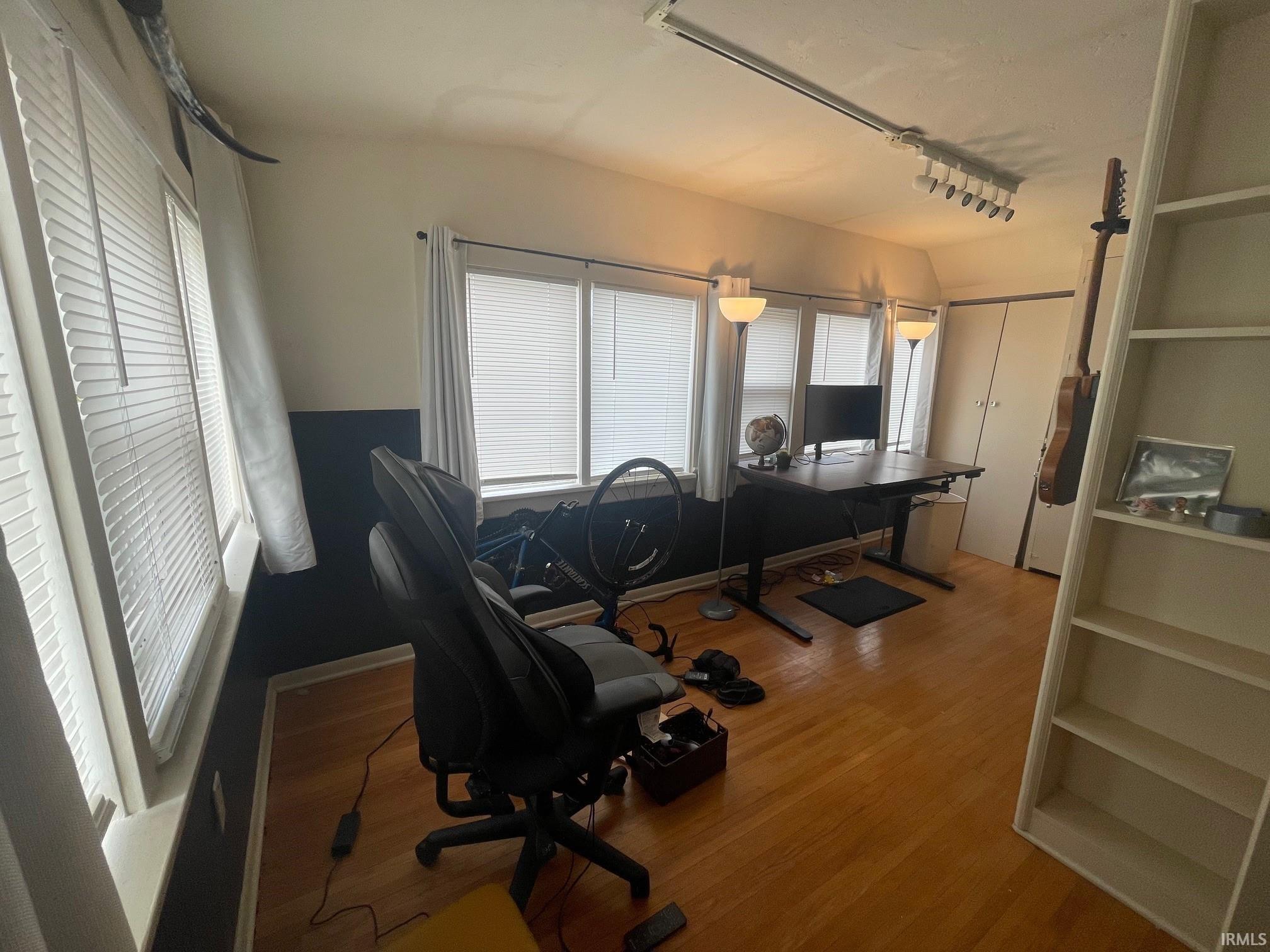Office with hard wood floors and built-in shelving.