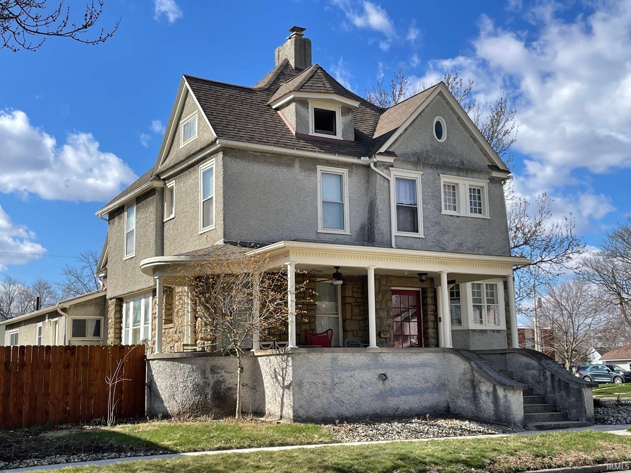 View of front of house with a porch, stucco siding, and a chimney.