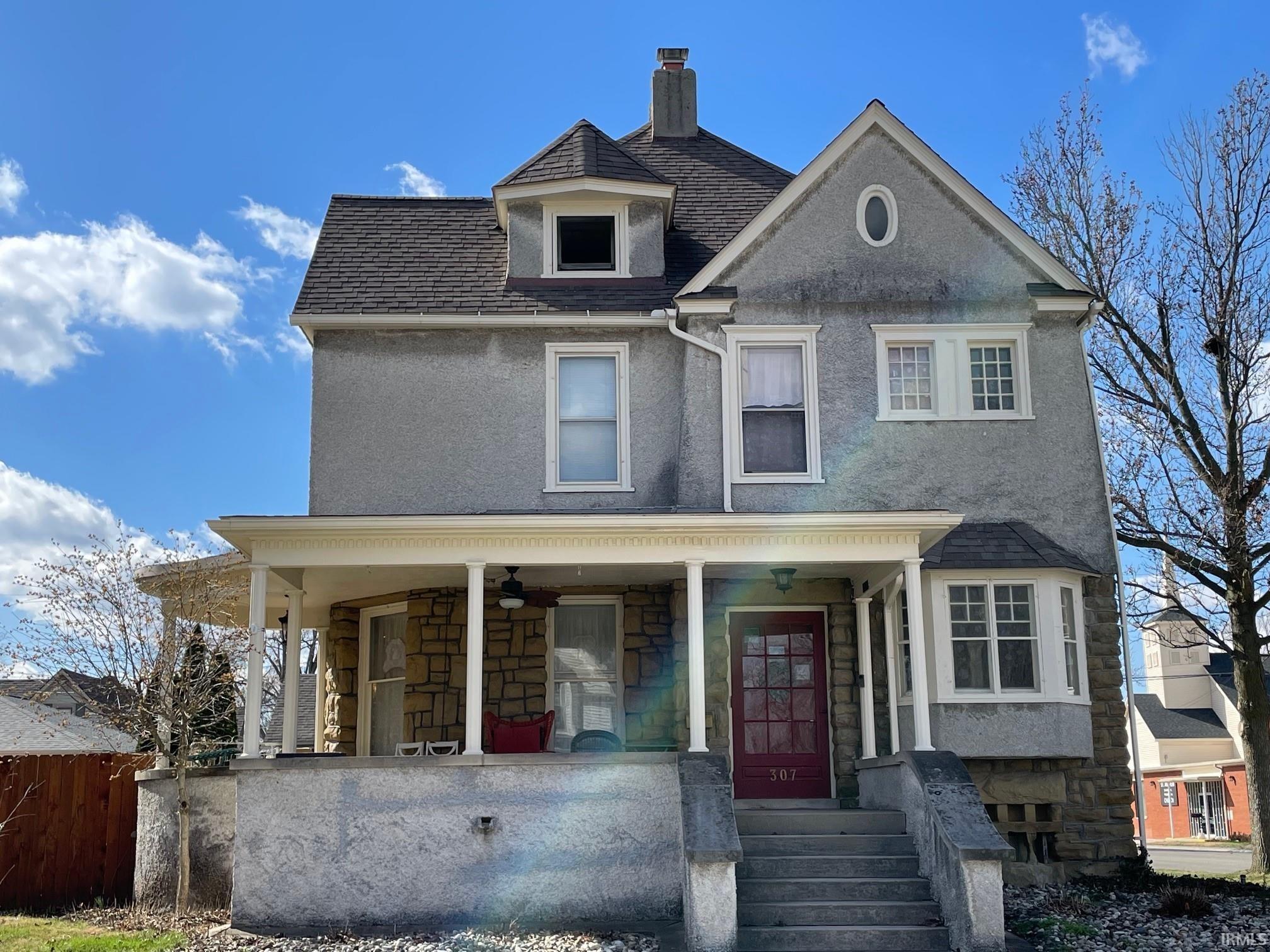View of front facade featuring stone siding, a porch, stucco siding, and brownstone block.