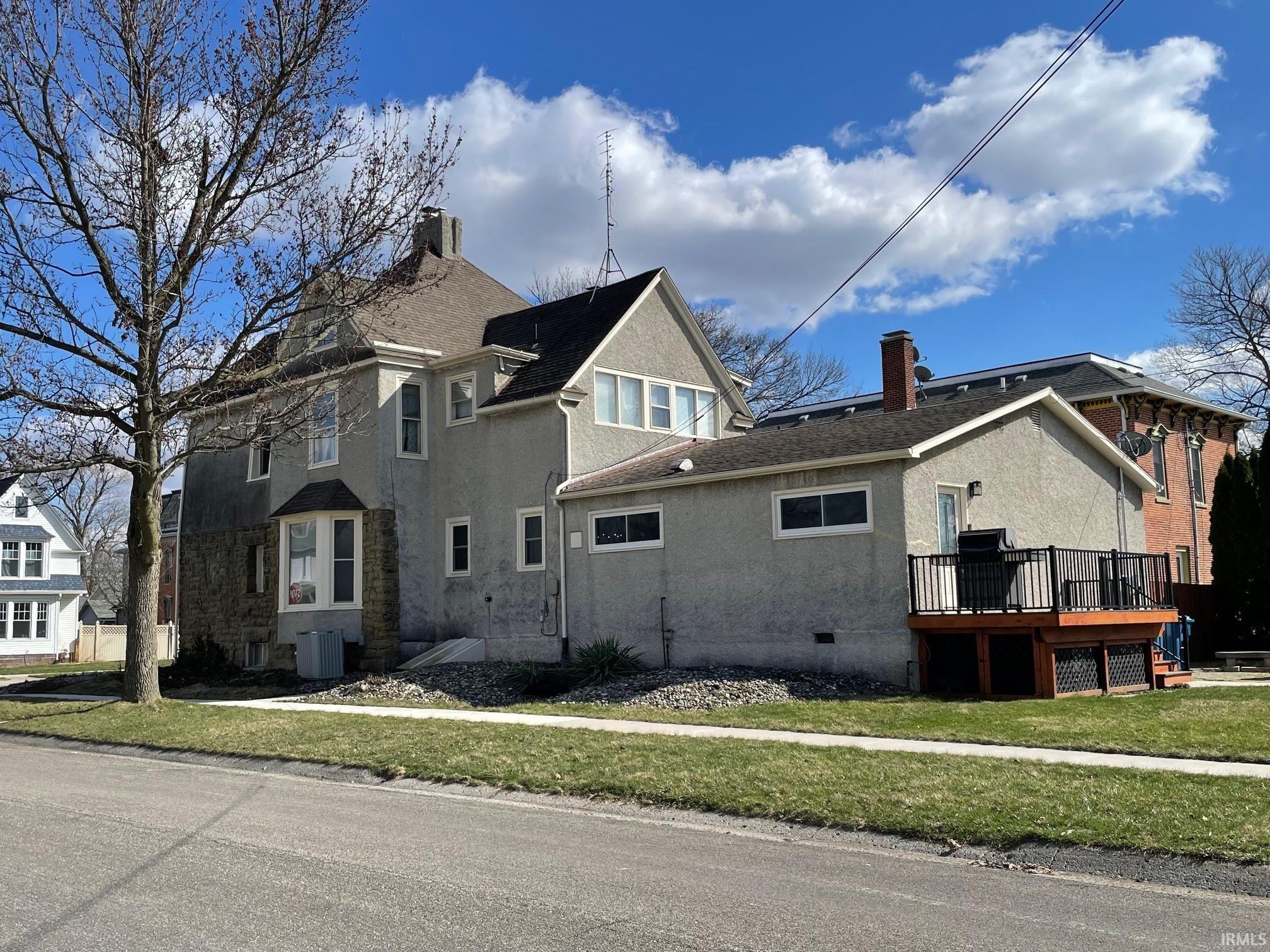 View of side of property featuring a yard, a deck, crawl space, a chimney, and stucco siding