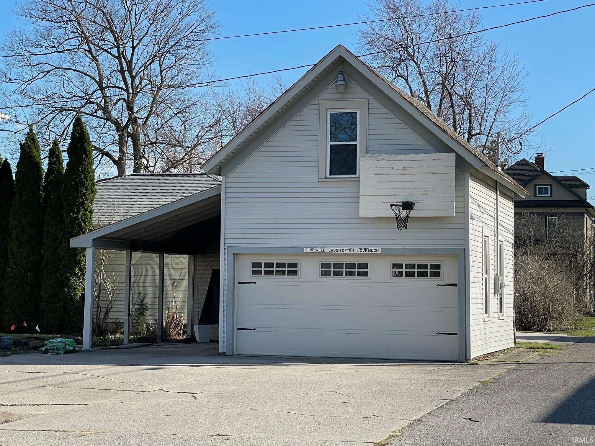 View of side of home with driveway and roof with shingles