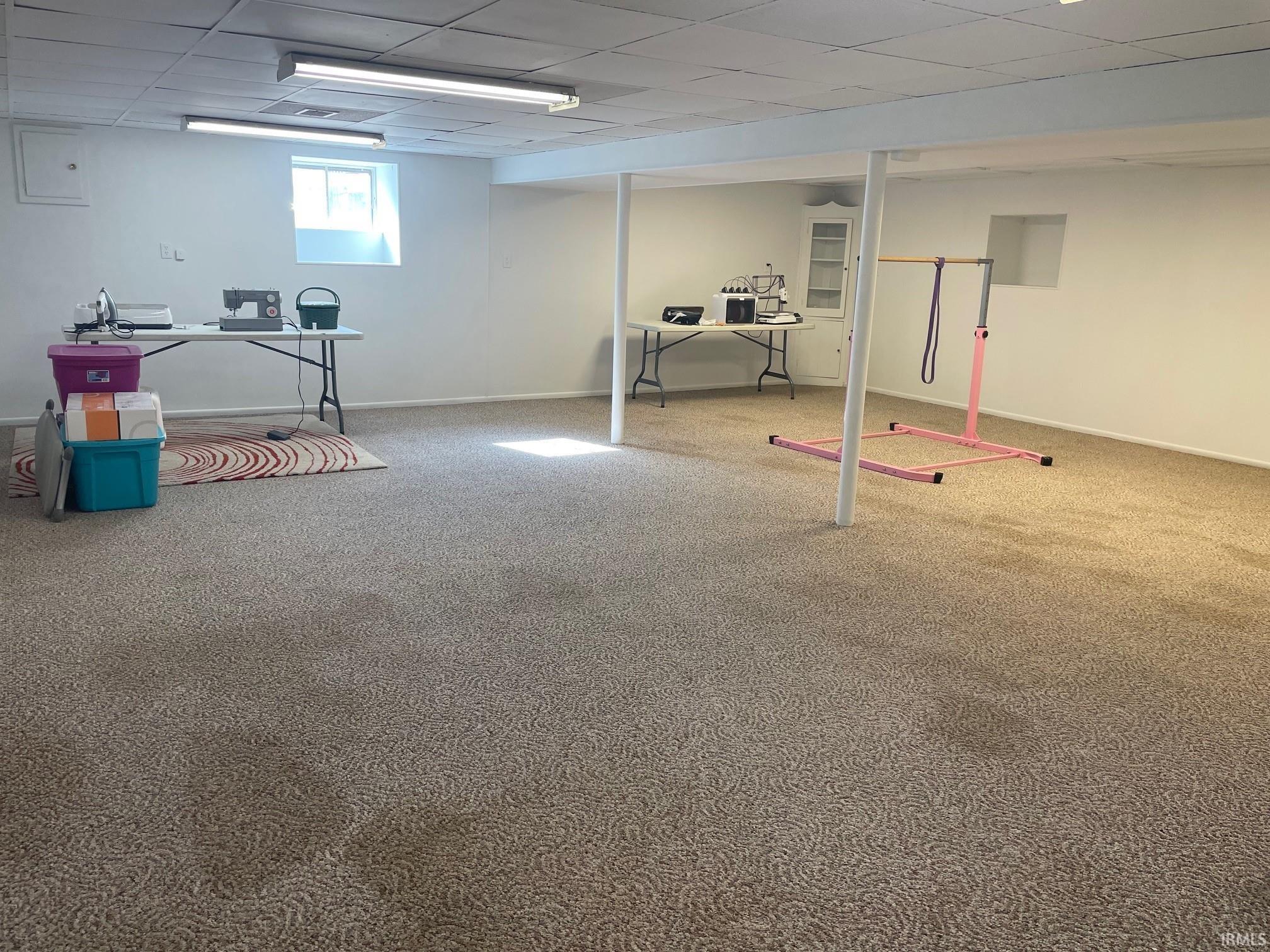 Below grade area featuring a drop ceiling and carpet flooring
