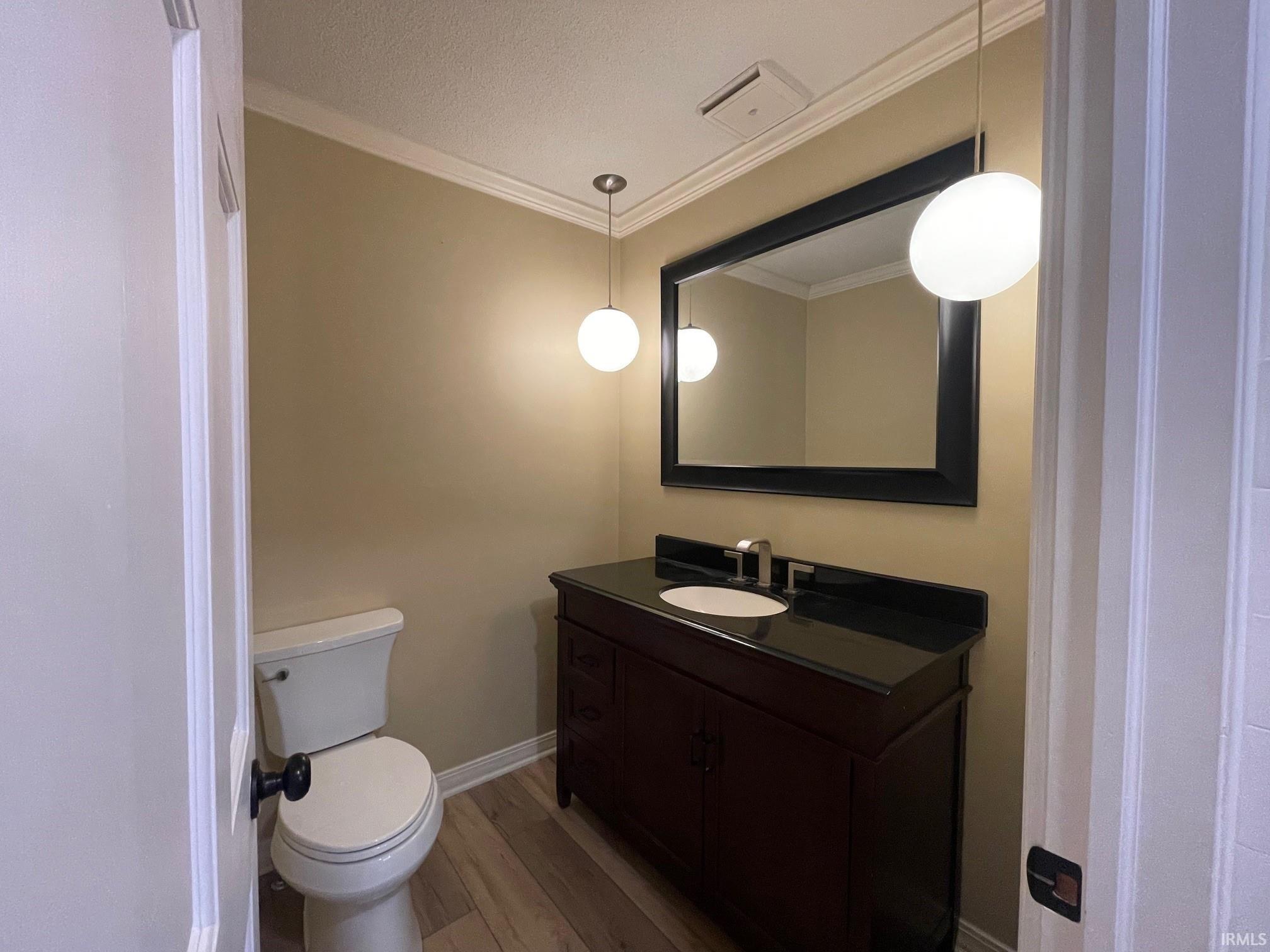 Bathroom with light wood-style floors, vanity, and ornamental molding