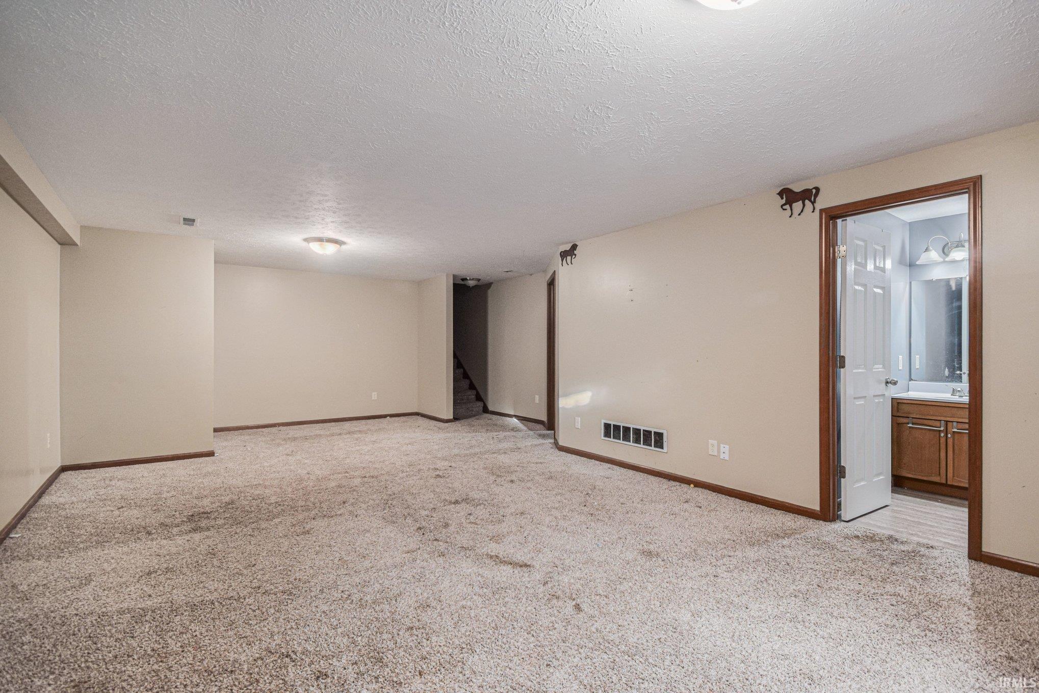Finished below grade area with light carpet and a textured ceiling