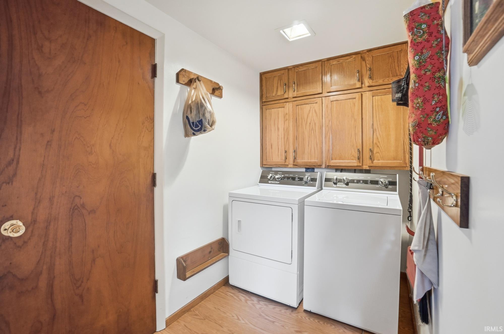 Laundry room featuring cabinet space, light wood-style floors, and washer and clothes dryer