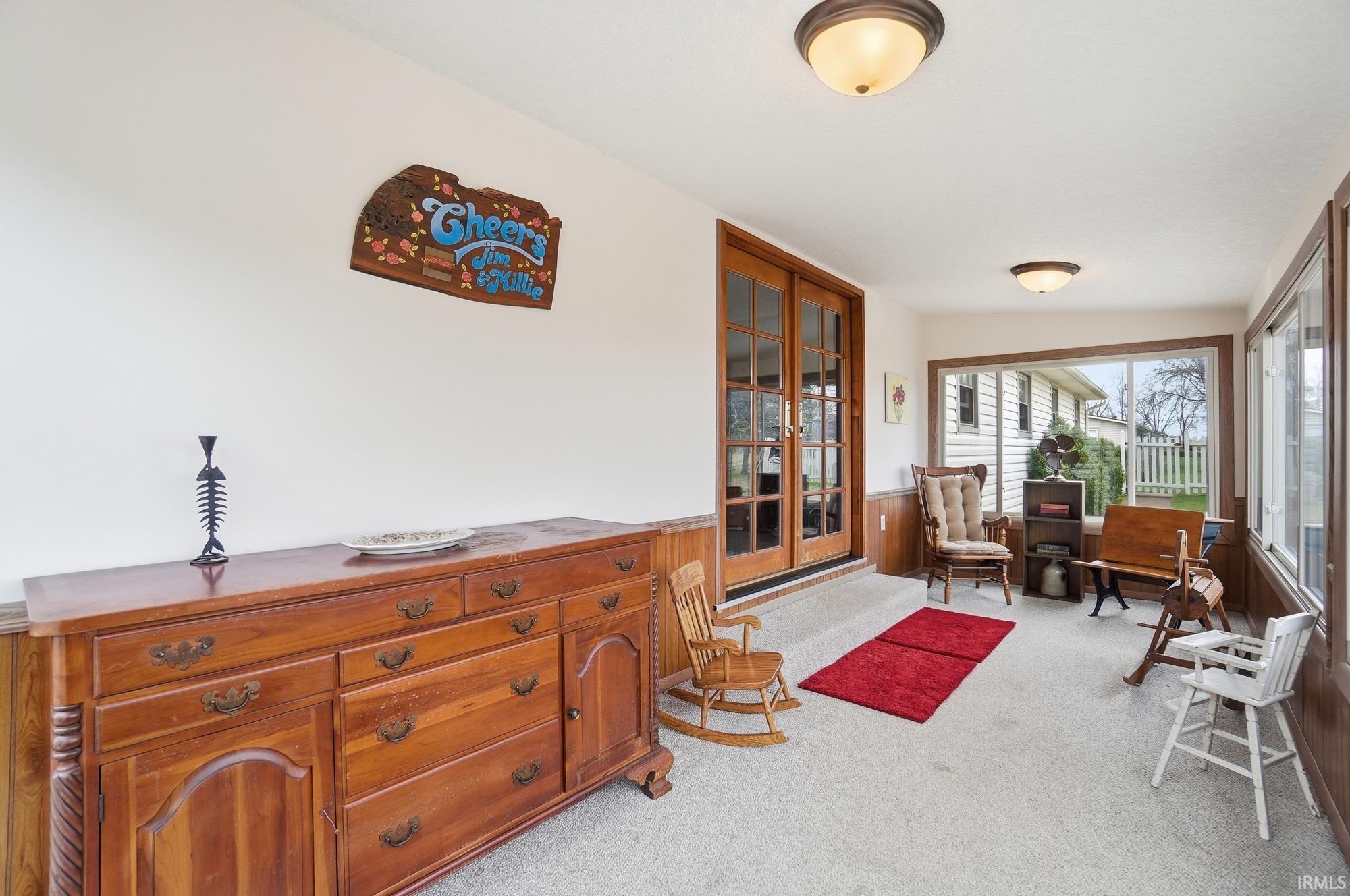 Sunroom / solarium featuring french doors, a wainscoted wall, carpet, and wood walls