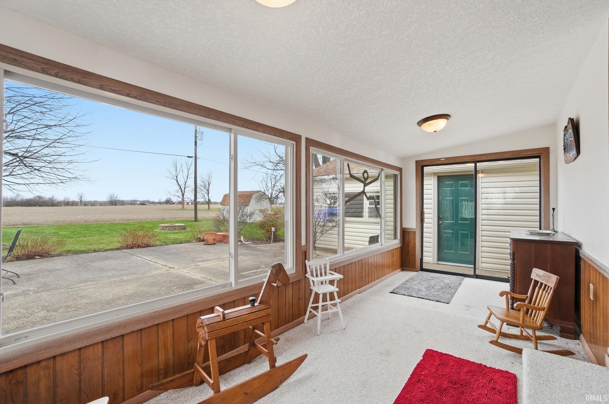 Sunroom / solarium featuring wooden walls, a wainscoted wall, and carpet floors