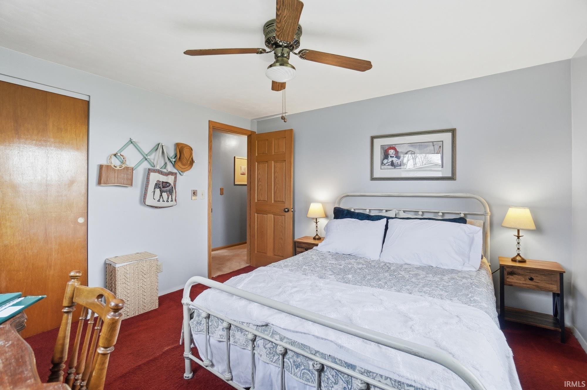 Bedroom with a ceiling fan, dark colored carpet, and a closet