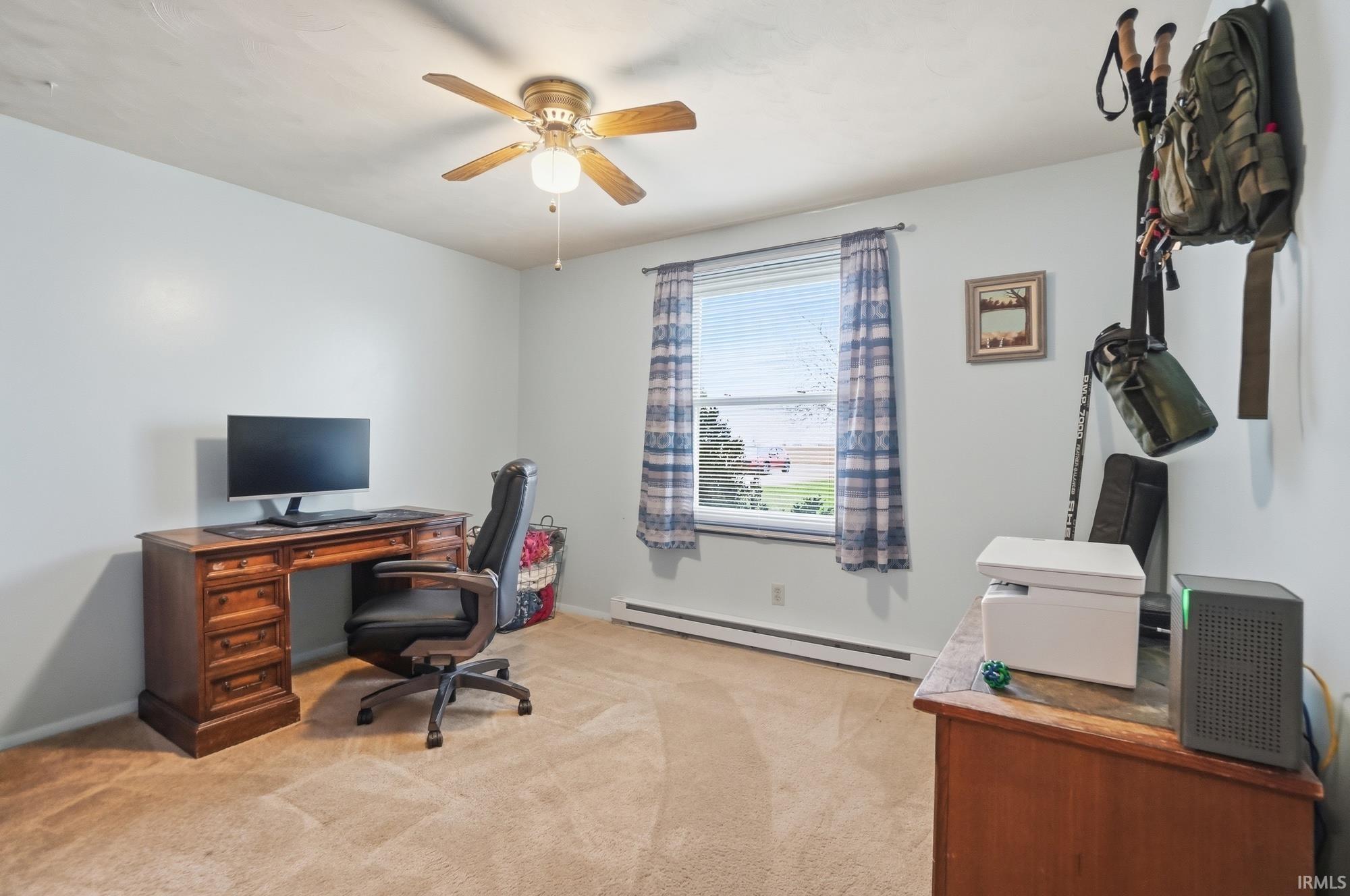 Office with baseboard heating, light carpet, and ceiling fan