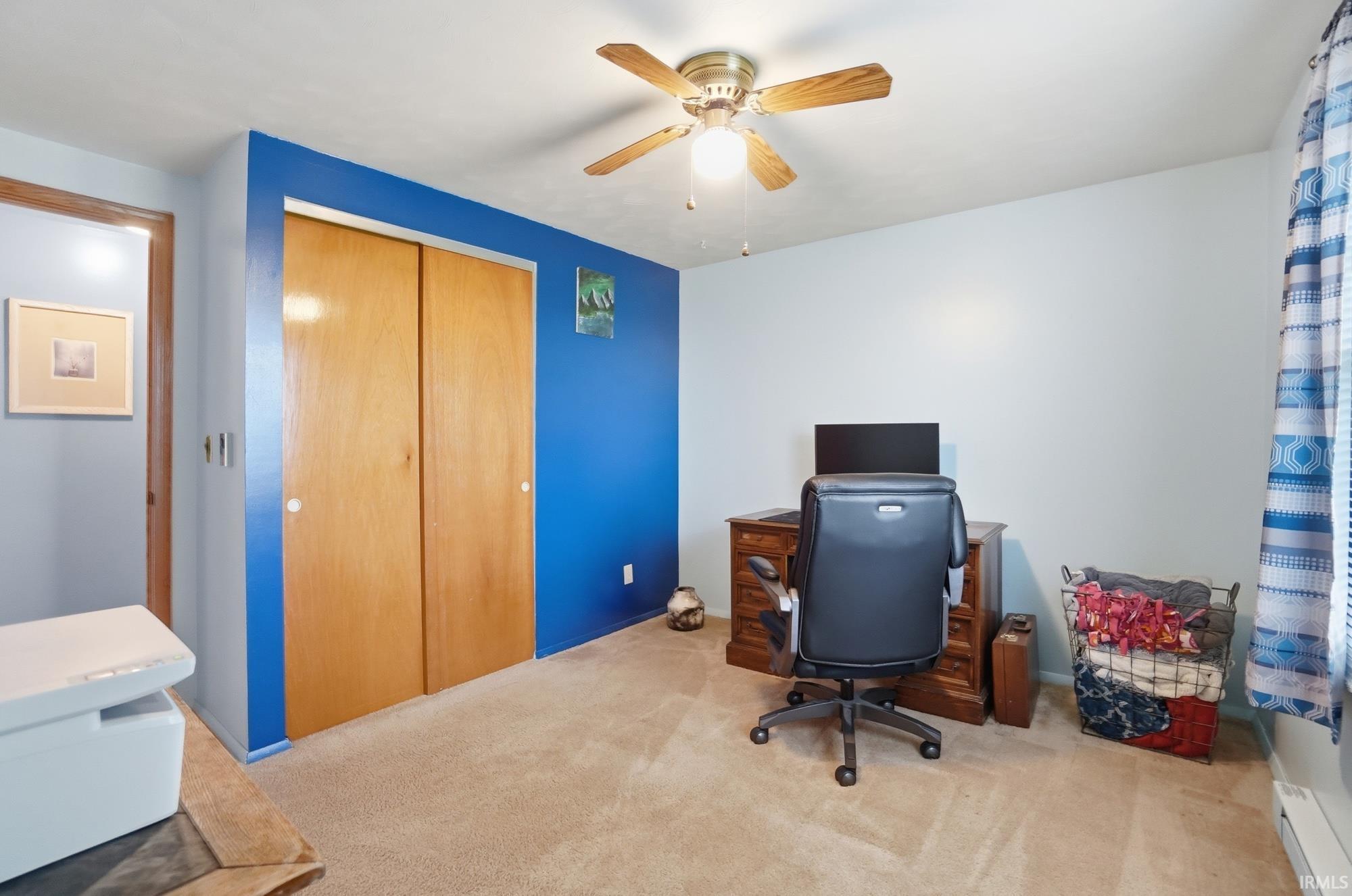 Home office with baseboard heating, light colored carpet, and a ceiling fan